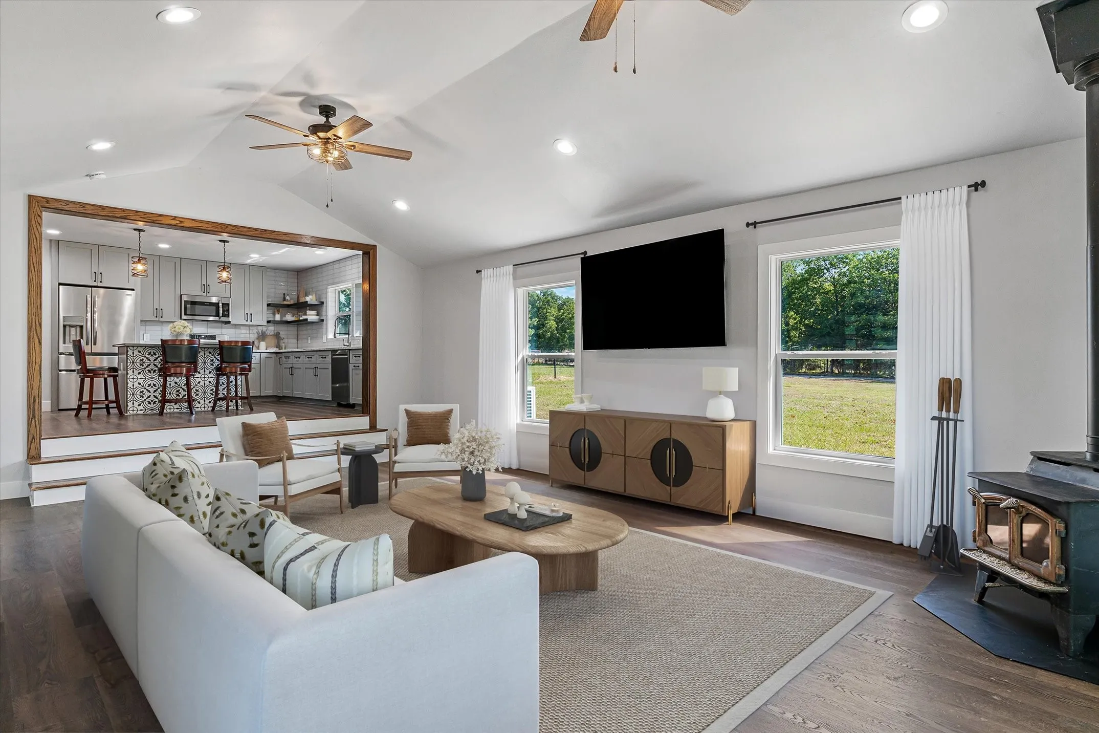 Digitally enhanced. Open-concept living space featuring wood-finish flooring, vaulted ceilings, and recessed lighting