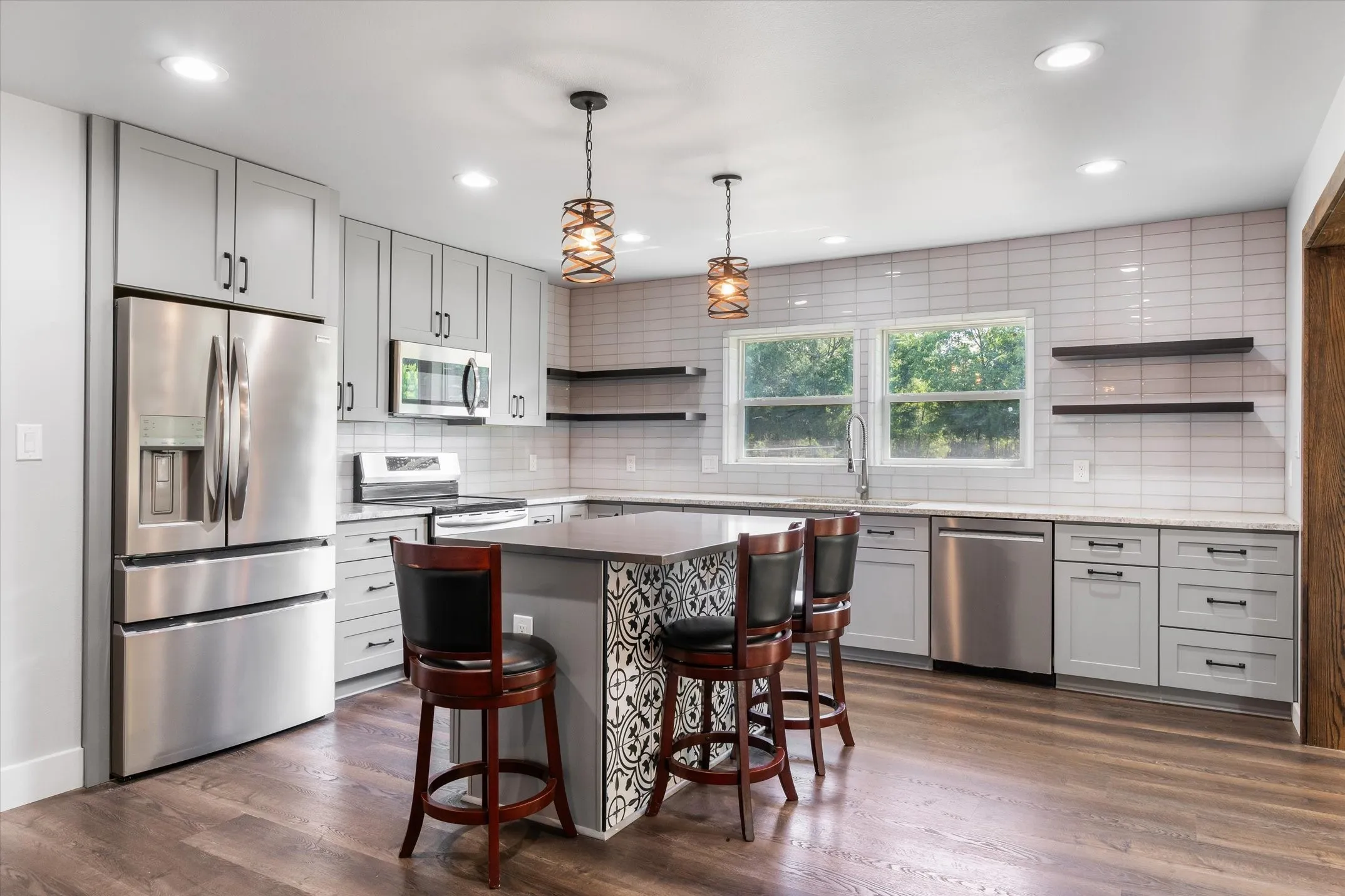 Modern kitchen featuring light gray cabinetry, stainless steel appliances, and wood-finish flooring