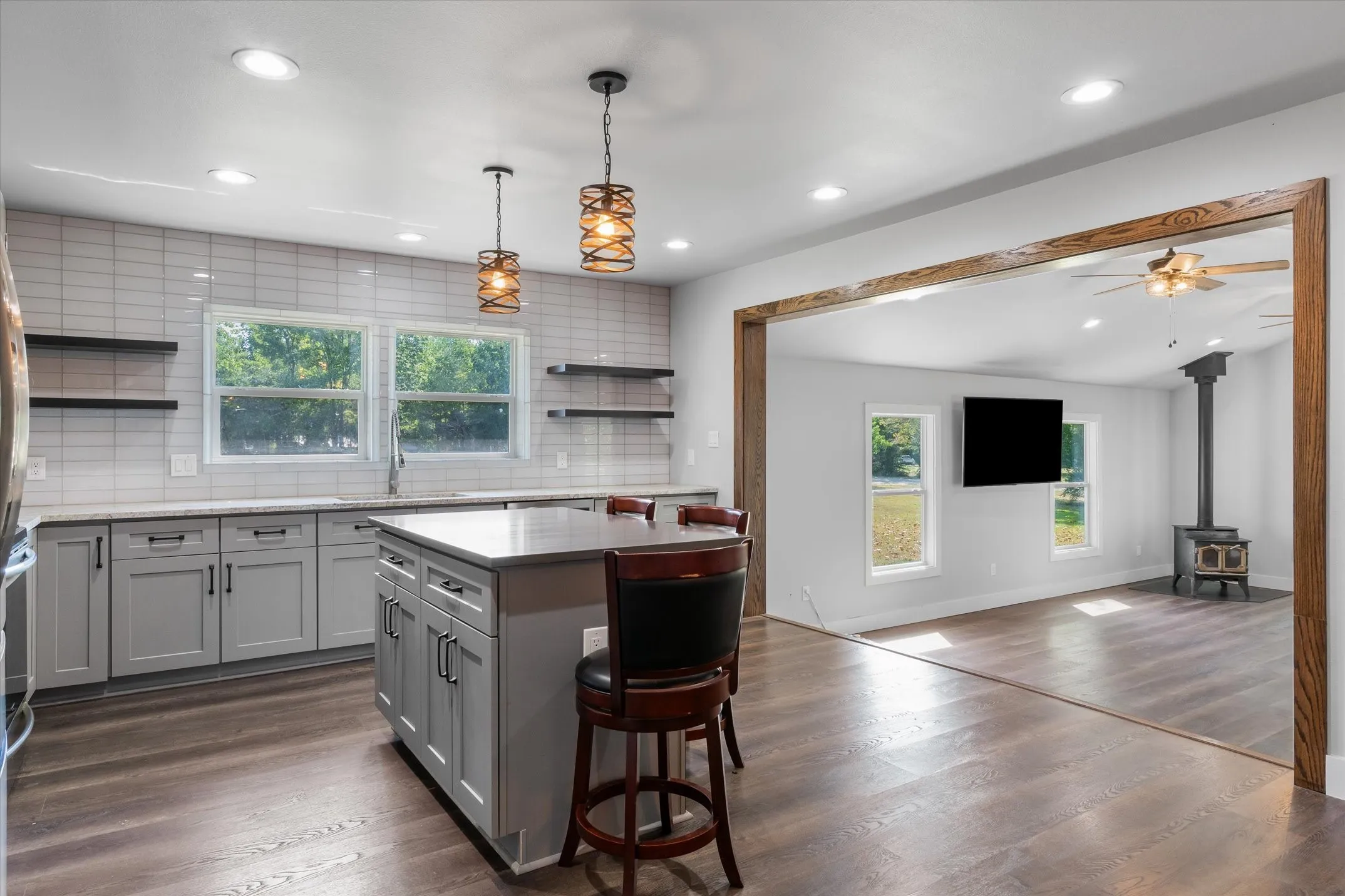 Modern kitchen featuring a central island, grey cabinetry, light subway tile backsplash, and wood-finish flooring