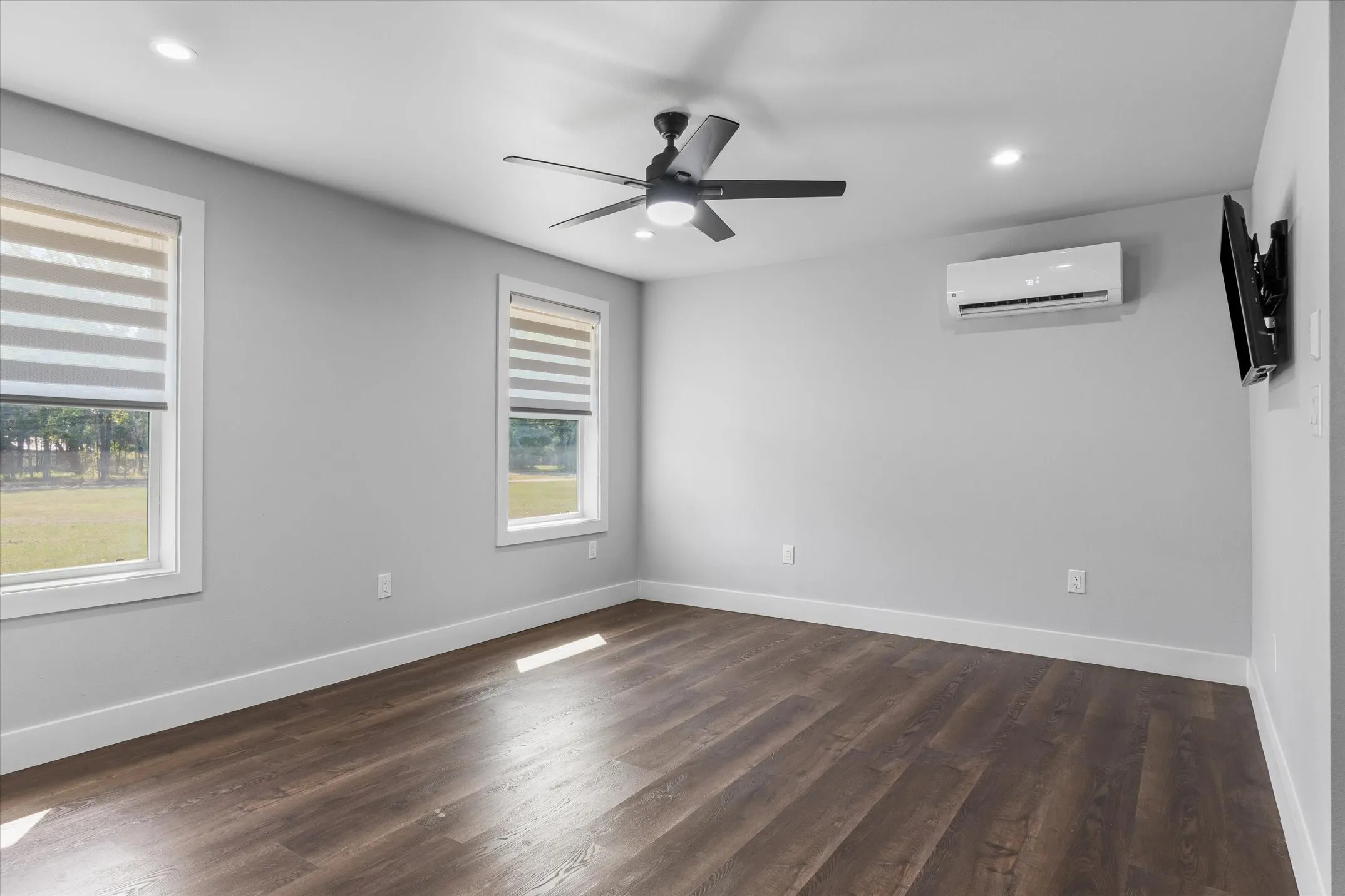 Spacious room featuring wood-finish flooring and light gray walls