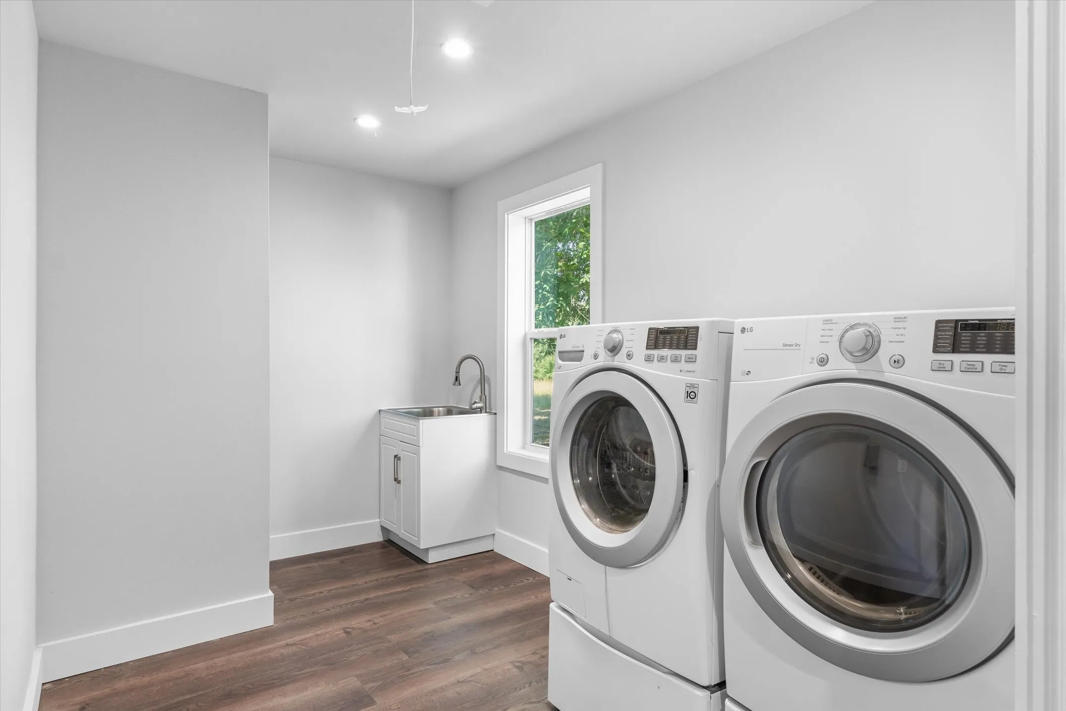 Dedicated laundry space featuring wood-finish flooring, white walls, and bright recessed lighting