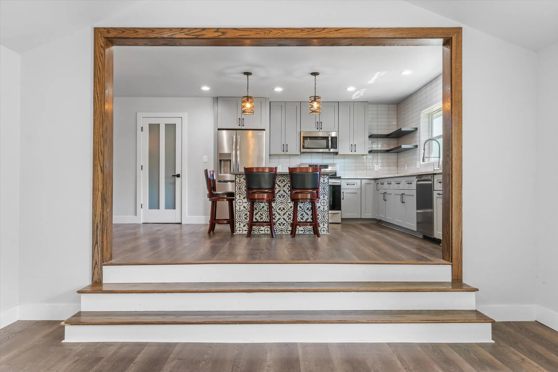 Open-concept kitchen featuring white cabinetry, stainless steel appliances, and a substantial island with decorative base panels and seating for multiple diners
