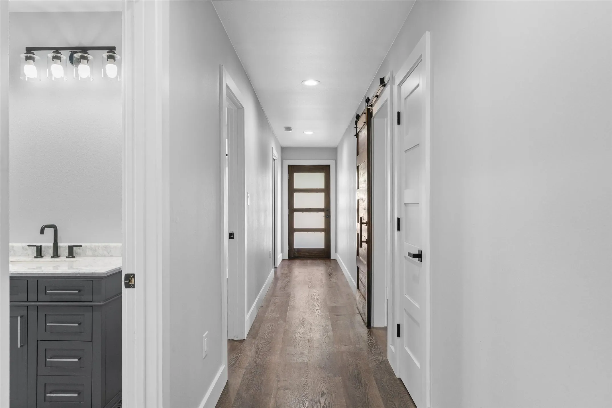 Hallway featuring wood-finish flooring, recessed lighting, and a modern barn door
