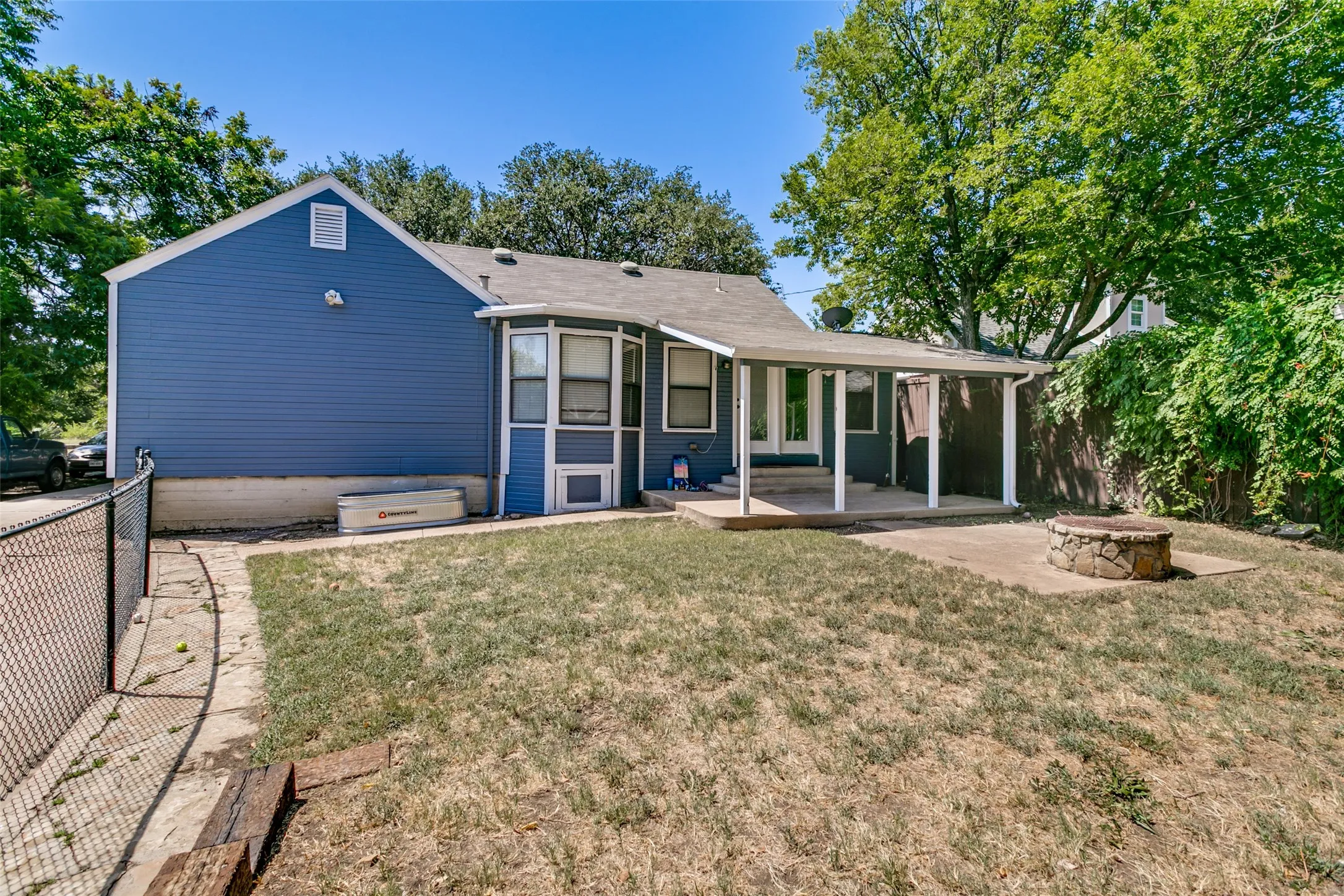 The back yard is fenced, has a covered patio and a fire pit.