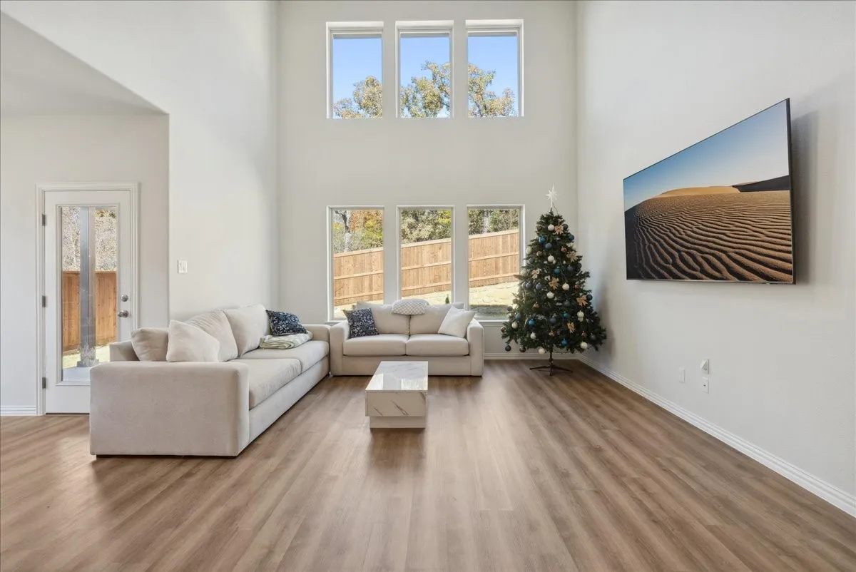 Living area with wood-finish flooring, high ceilings, and abundant natural light from multiple windows