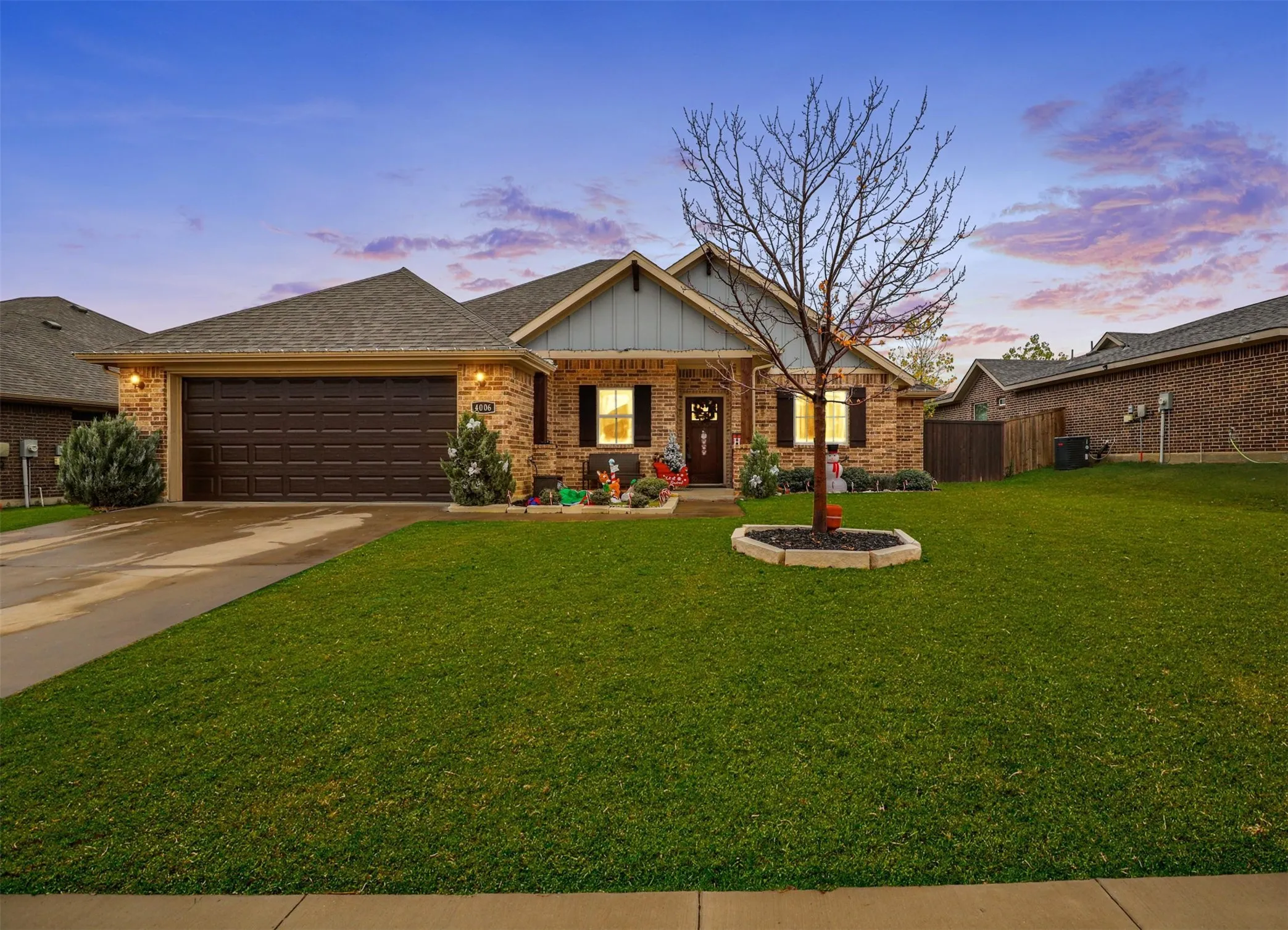 Stone and siding exterior with a dark brown garage door, front entry with a dark wood door, and a concrete driveway