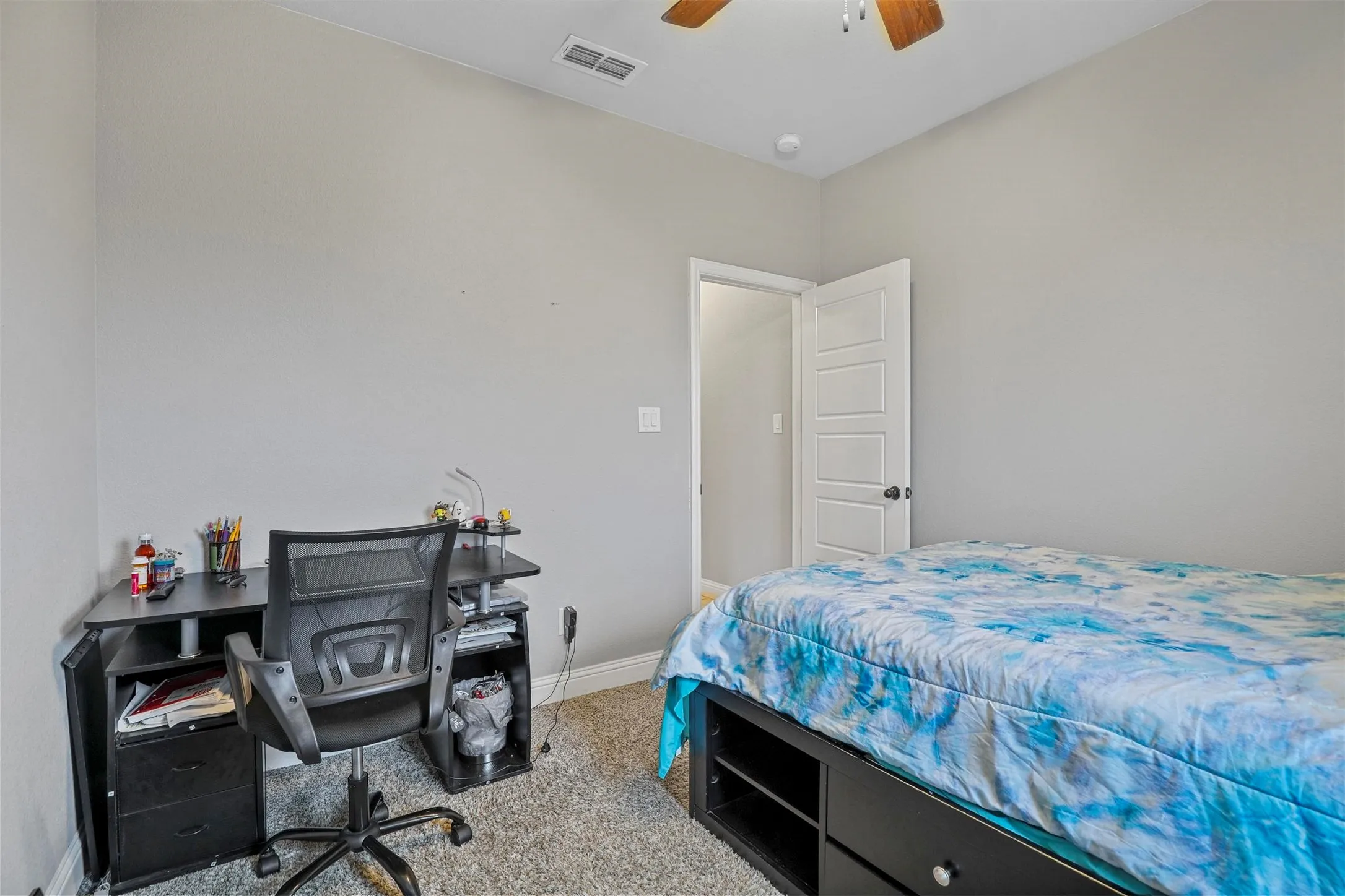 Bedroom featuring light gray walls, textured carpeting, and a ceiling fan