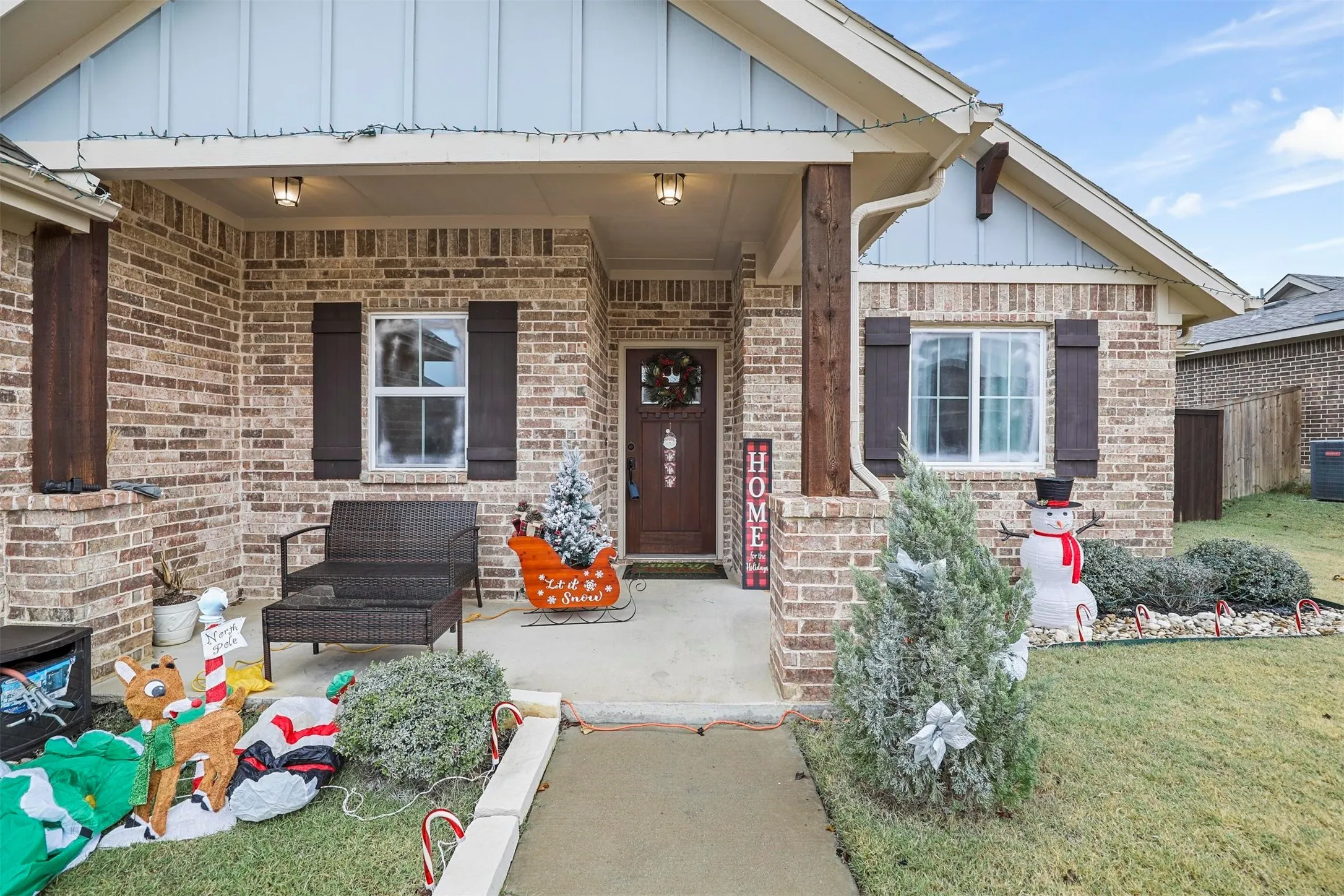 Brick exterior featuring wood shutters and a covered porch