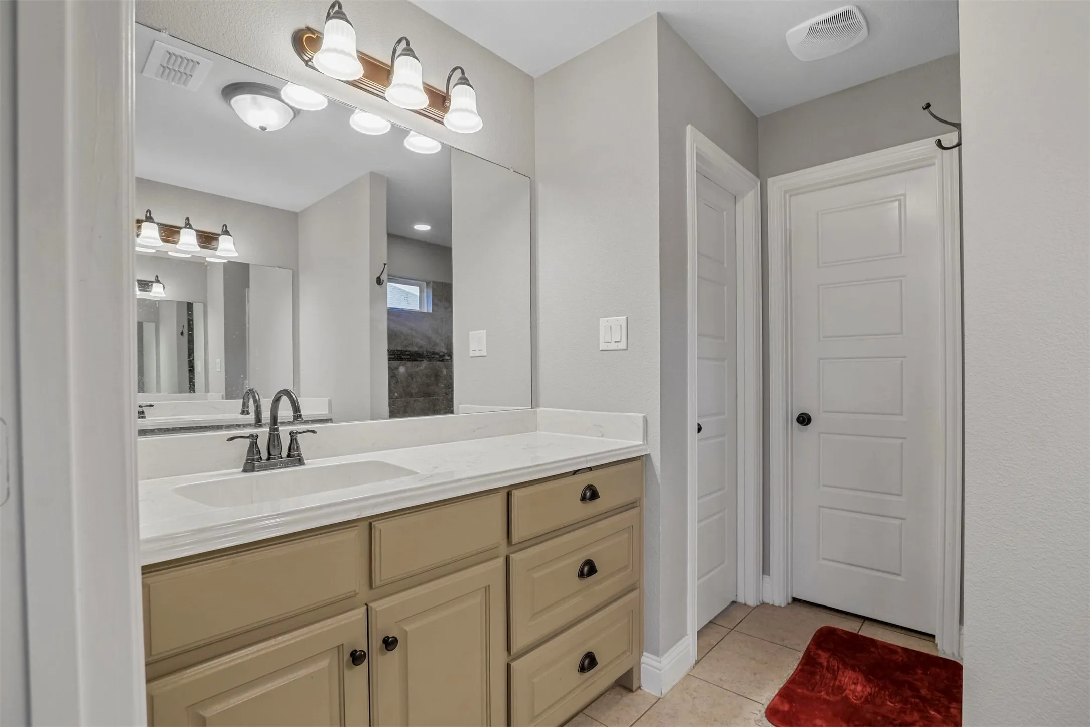 Bathroom vanity featuring a single basin, light-toned countertop, and wood-finish cabinetry