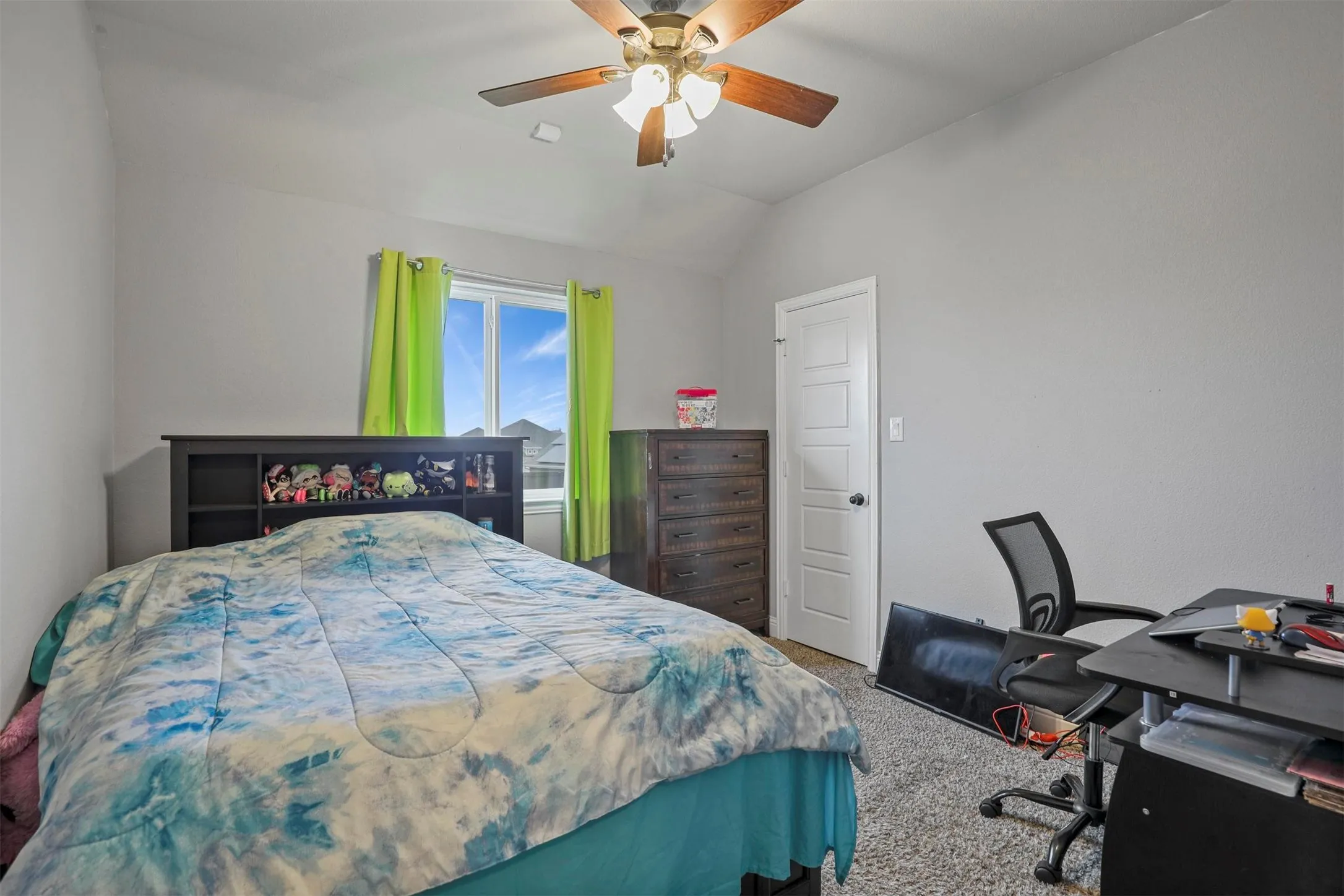 Bedroom featuring a vaulted ceiling with a ceiling fan, a window with exterior views, light gray wall paint, and carpet flooring