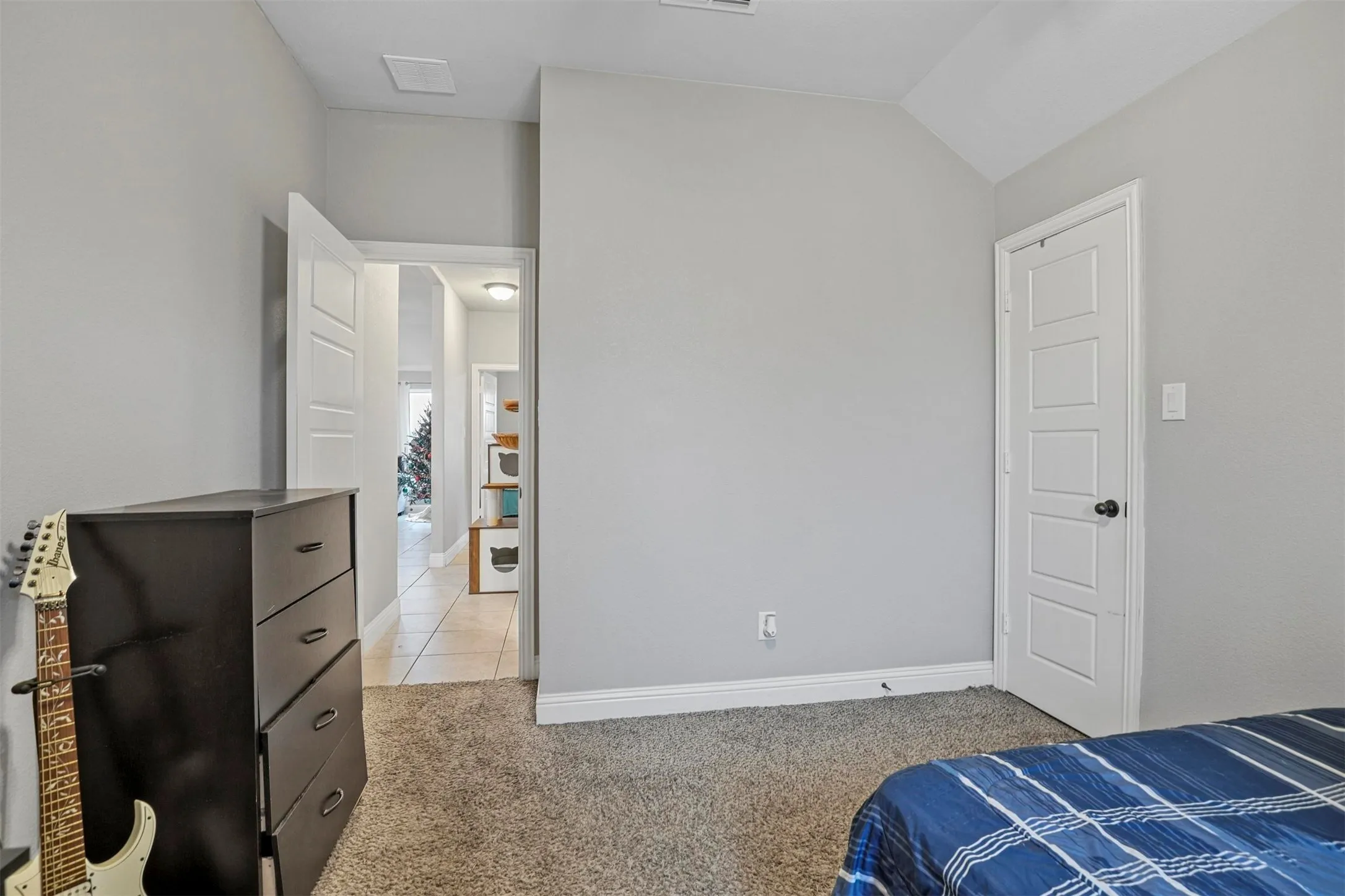 Carpeted interior space featuring light grey walls, white baseboards, and a vaulted ceiling