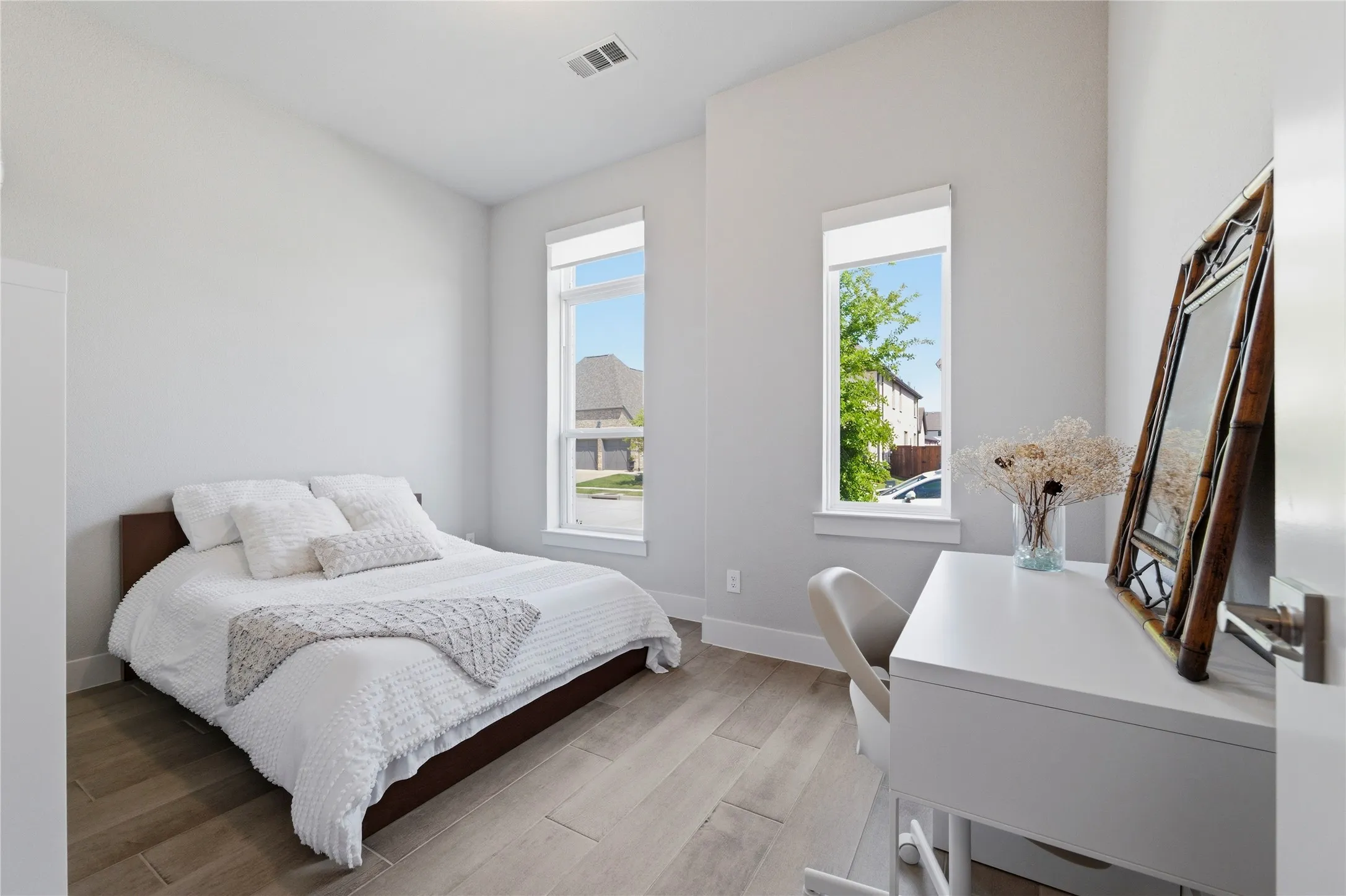 Bedroom with light wood finished floors and an office area