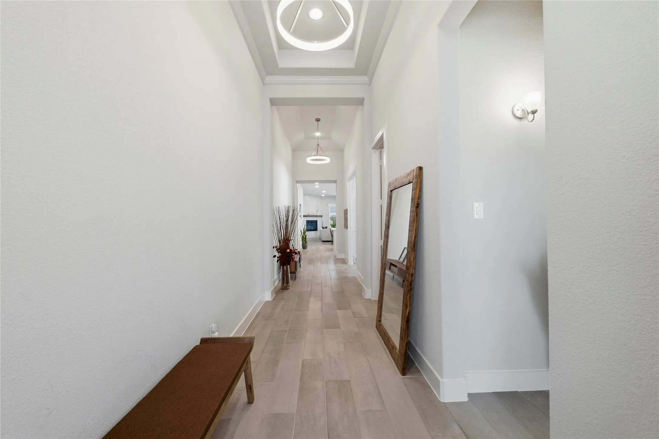 Corridor with light wood-style flooring and a high tray ceiling