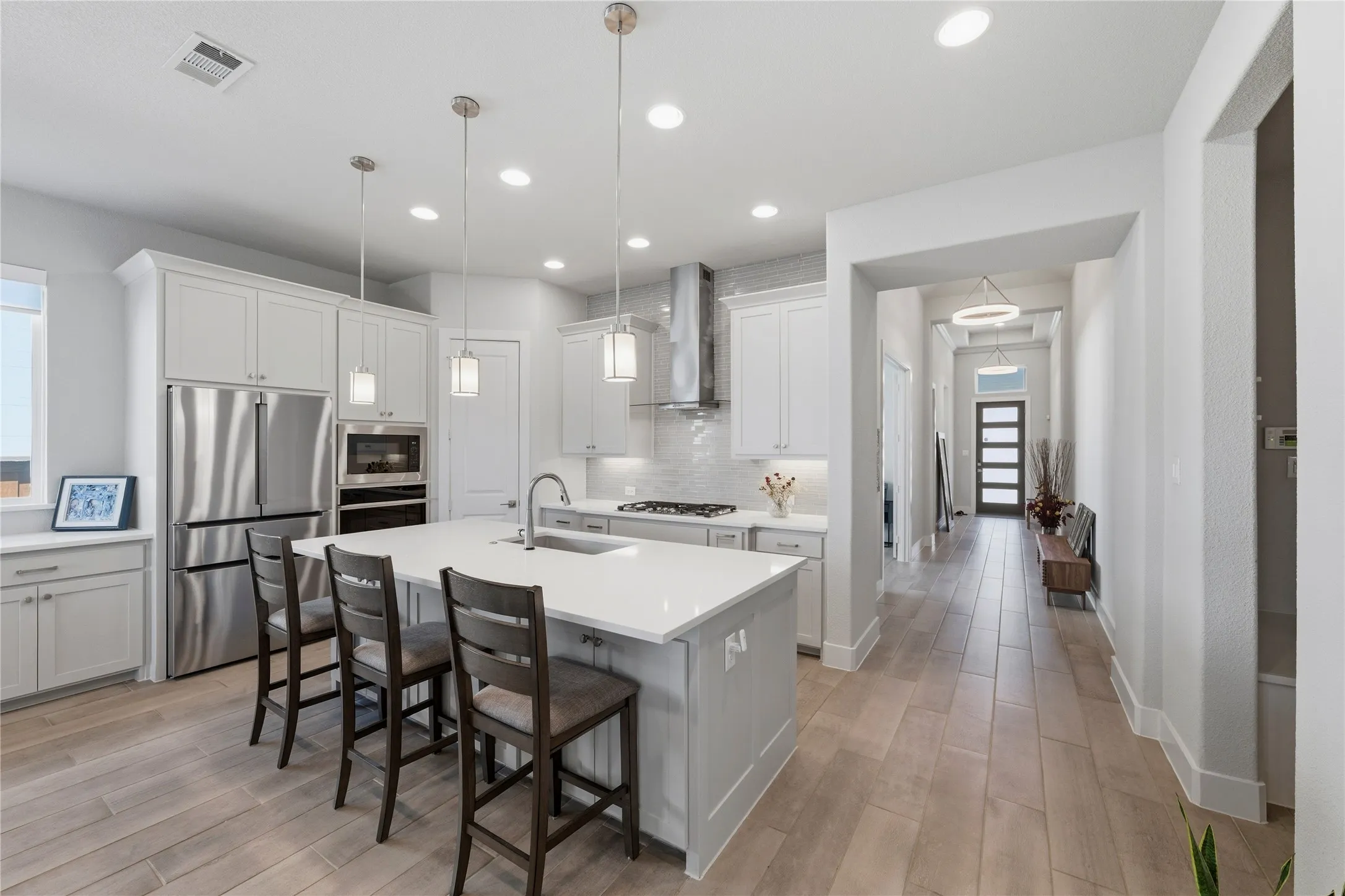 Kitchen featuring stainless steel appliances, a kitchen breakfast bar, a center island with sink, and white cabinets