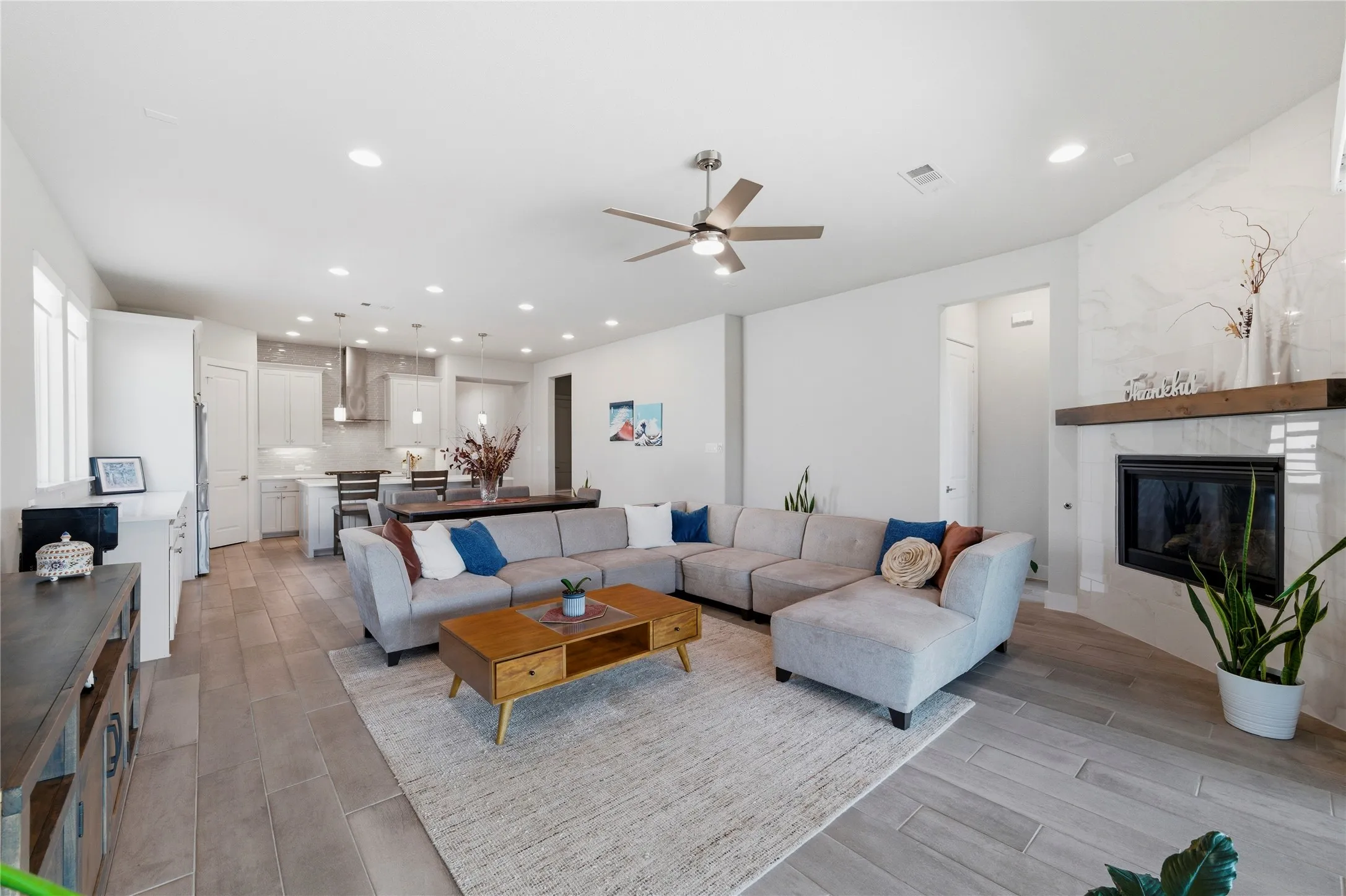 Dining space with light wood finished floors, a ceiling fan, a glass covered fireplace, and recessed lighting