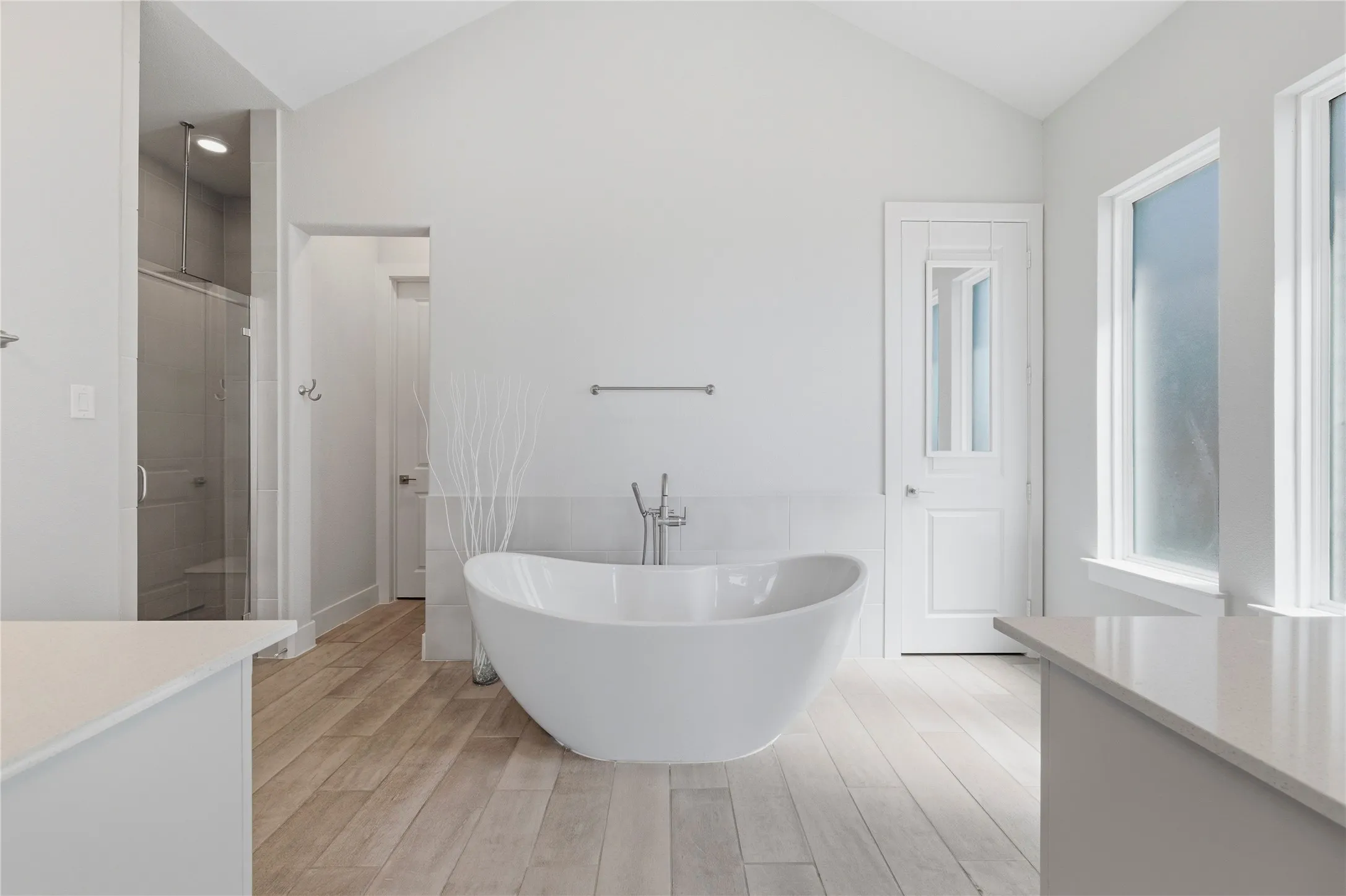 Full bathroom featuring vanity, a stall shower, a freestanding tub, light wood finished floors, and lofted ceiling