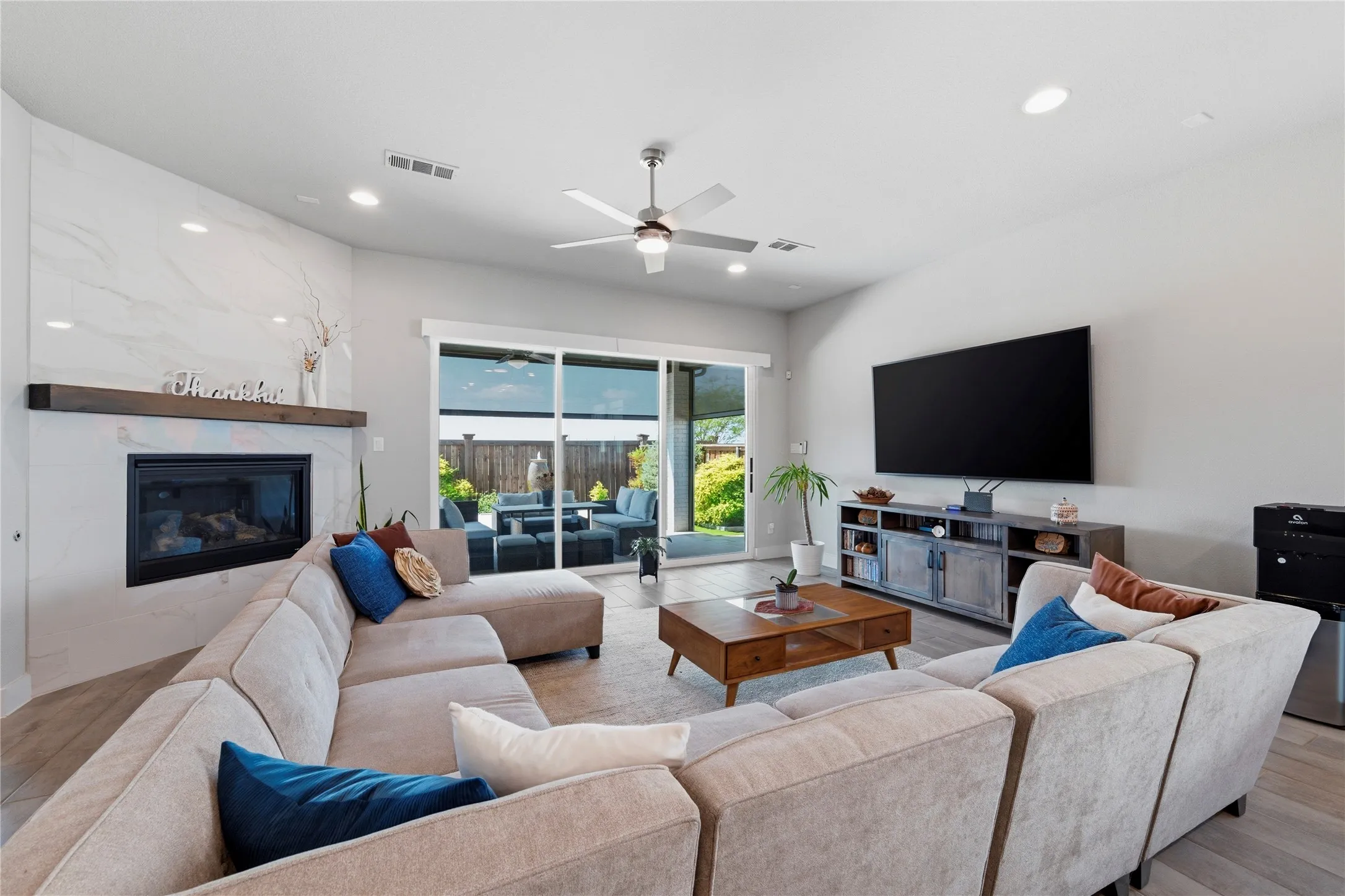 Living room with light wood-style flooring, a ceiling fan, a premium fireplace, and recessed lighting