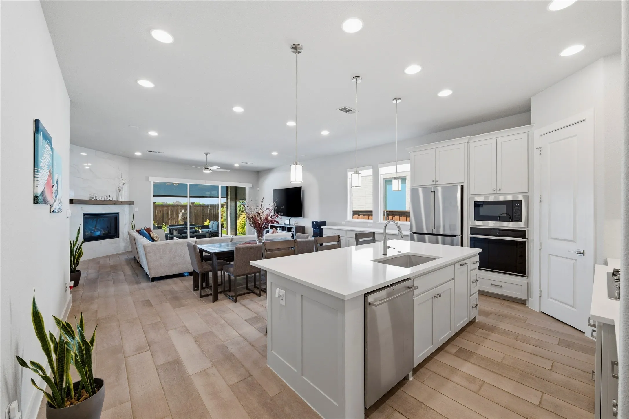 Kitchen with white cabinetry, a glass covered fireplace, an island with sink, stainless steel appliances, and open floor plan