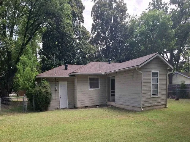 Rear exterior with neutral siding, a brown shingle roof, and gutters