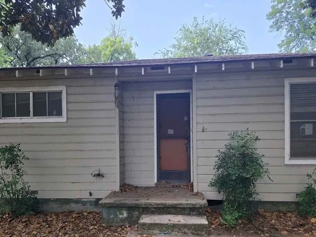 Single-story exterior featuring horizontal siding, a concrete stoop with two steps, a prominent entry door, and multiple windows