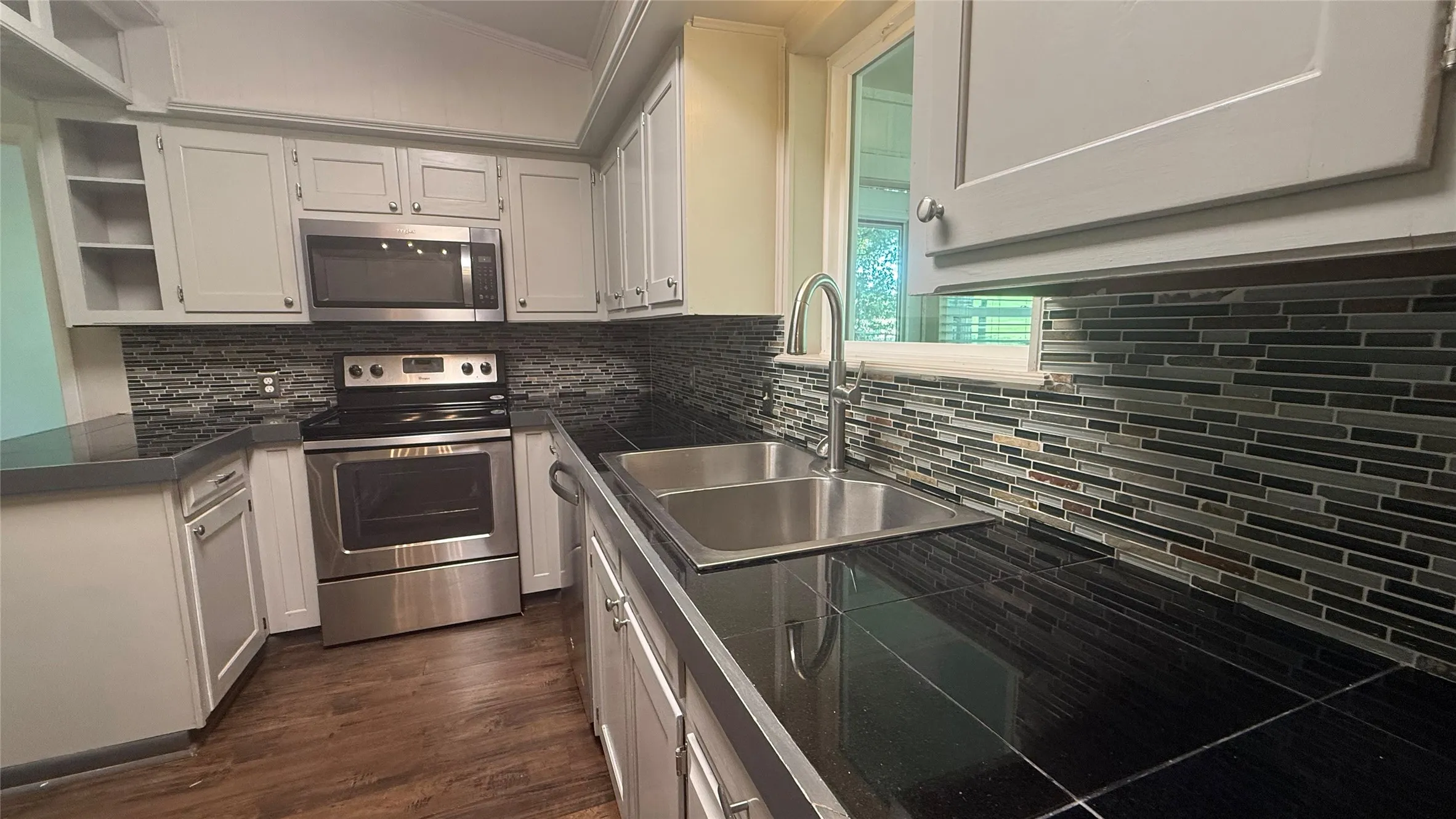 Kitchen featuring wood-finish flooring and light-toned cabinetry