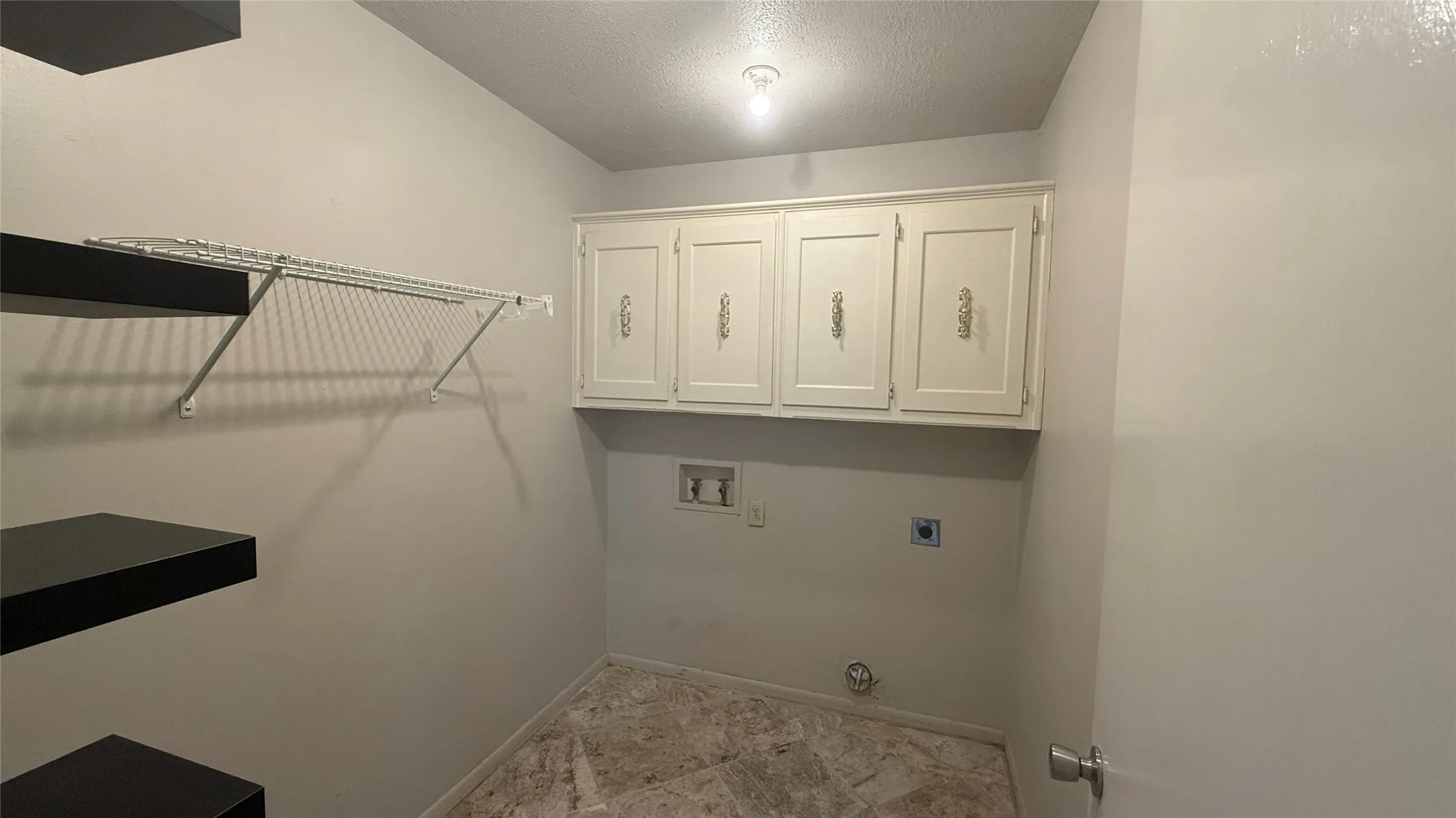 Laundry area featuring overhead cabinetry, built-in shelving, a wire rack, and a hard-surface flooring