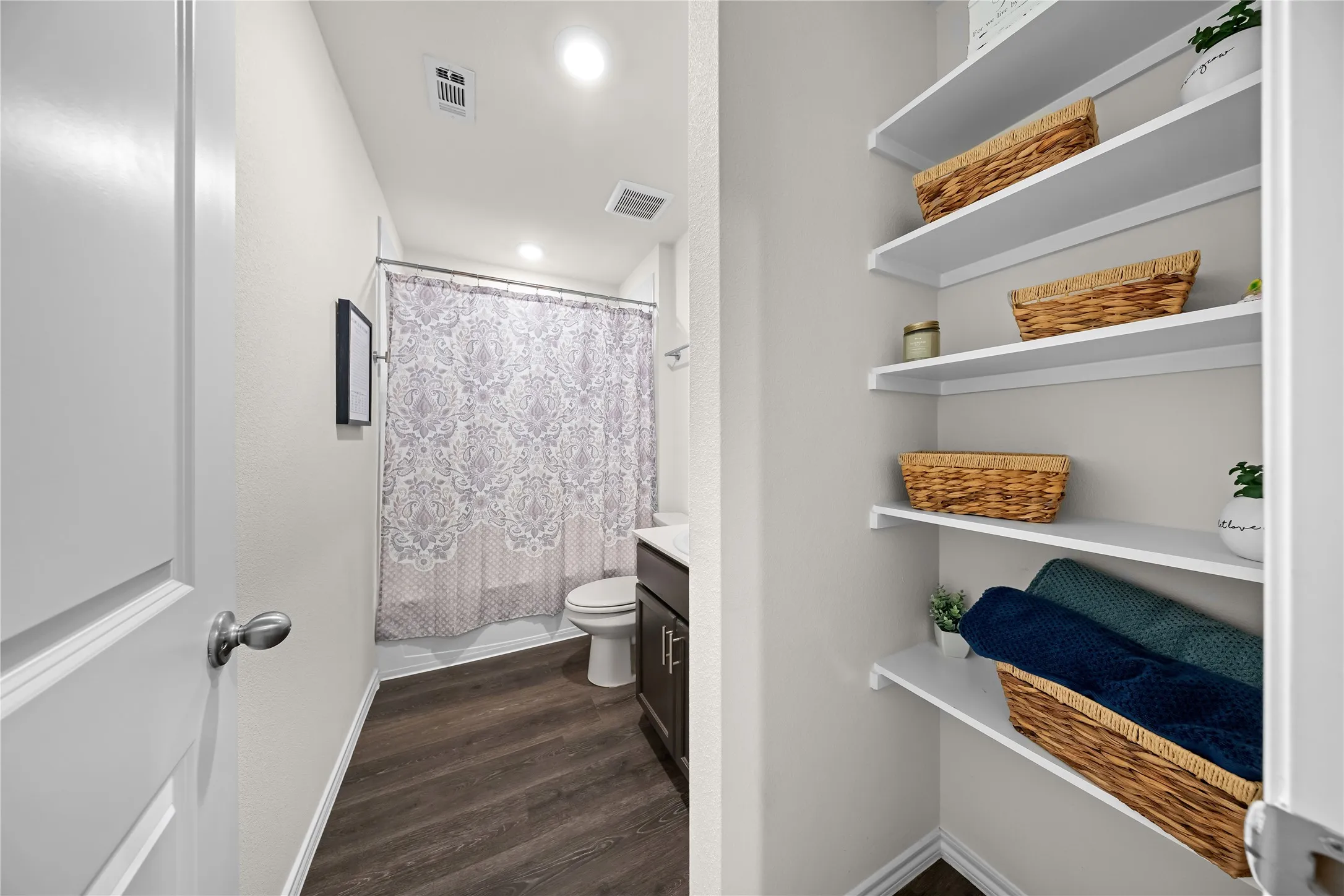 Full bathroom featuring wood-finish flooring, a white toilet, and a dark wood-finish vanity with a white countertop