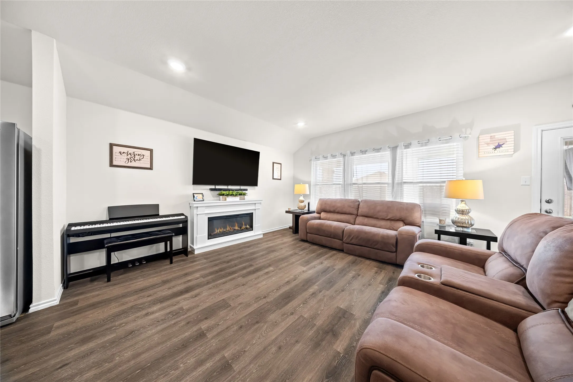 Spacious interior featuring wood-finish flooring, a contemporary fireplace with a white mantel, and multiple windows providing natural light