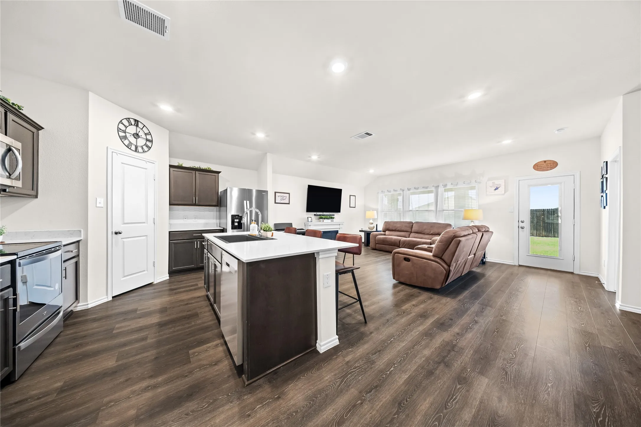 Open-concept living space featuring wood-finish flooring, recessed lighting, and white walls
