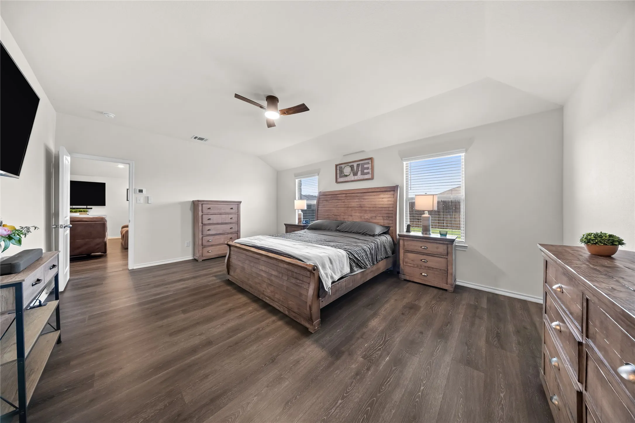 Spacious bedroom featuring dark wood-finish flooring, vaulted ceilings, and light-toned walls