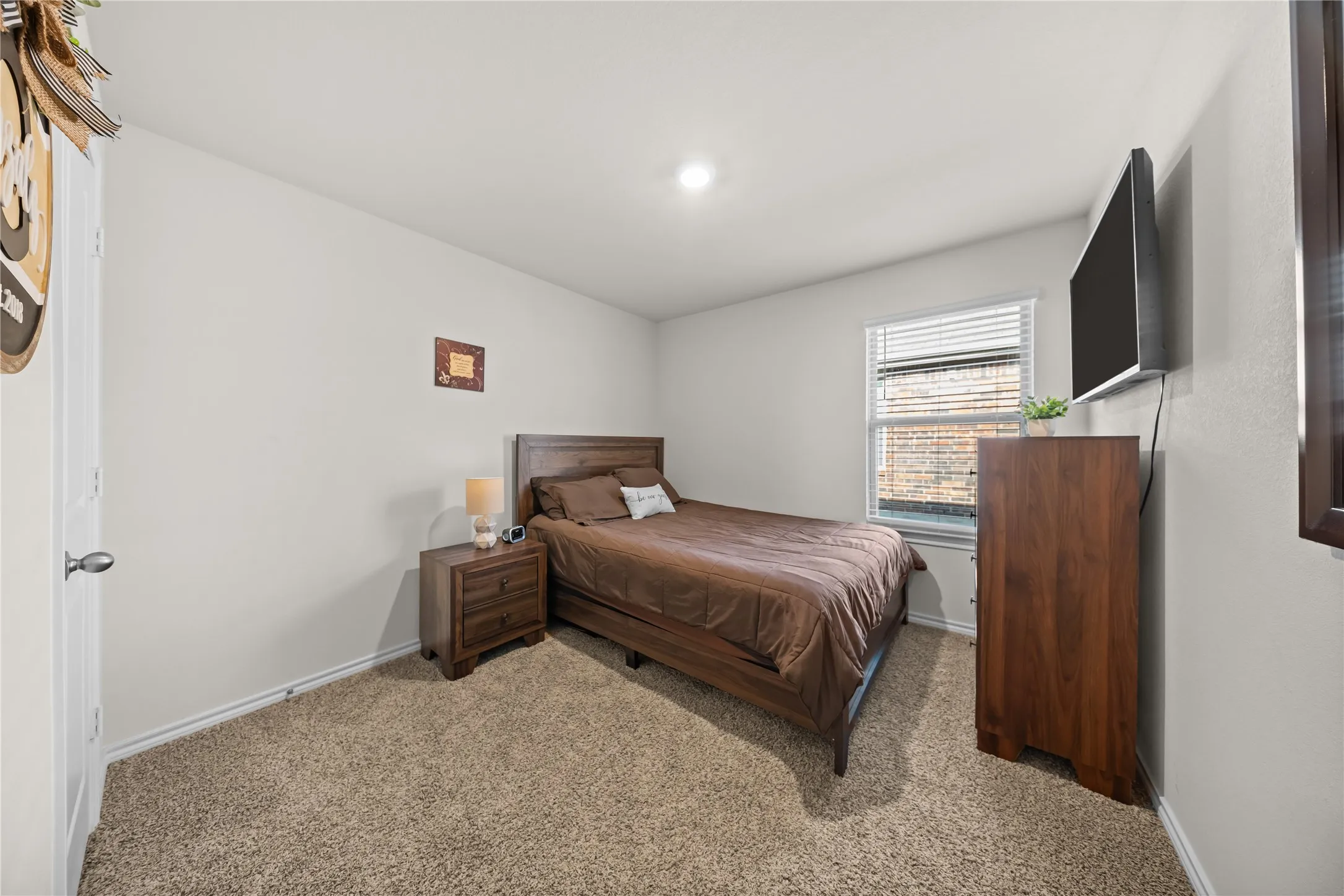 Bedroom featuring neutral wall paint, textured carpeting, a single window with horizontal blinds, and a recessed ceiling light