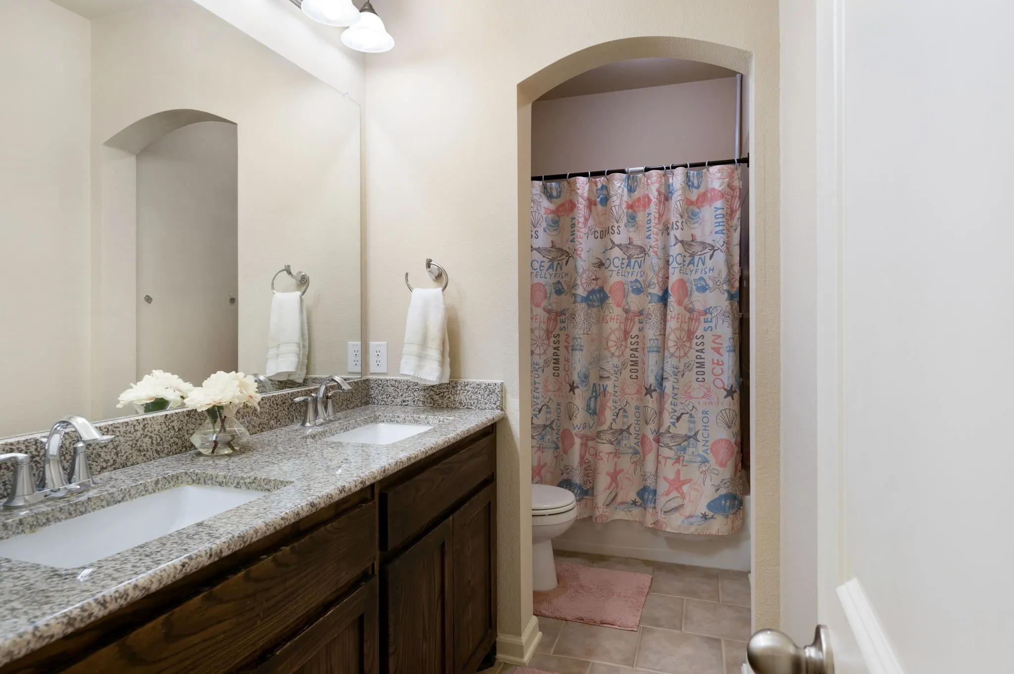Bathroom featuring a dual vanity with a speckled countertop, undermount sinks, and chrome faucets