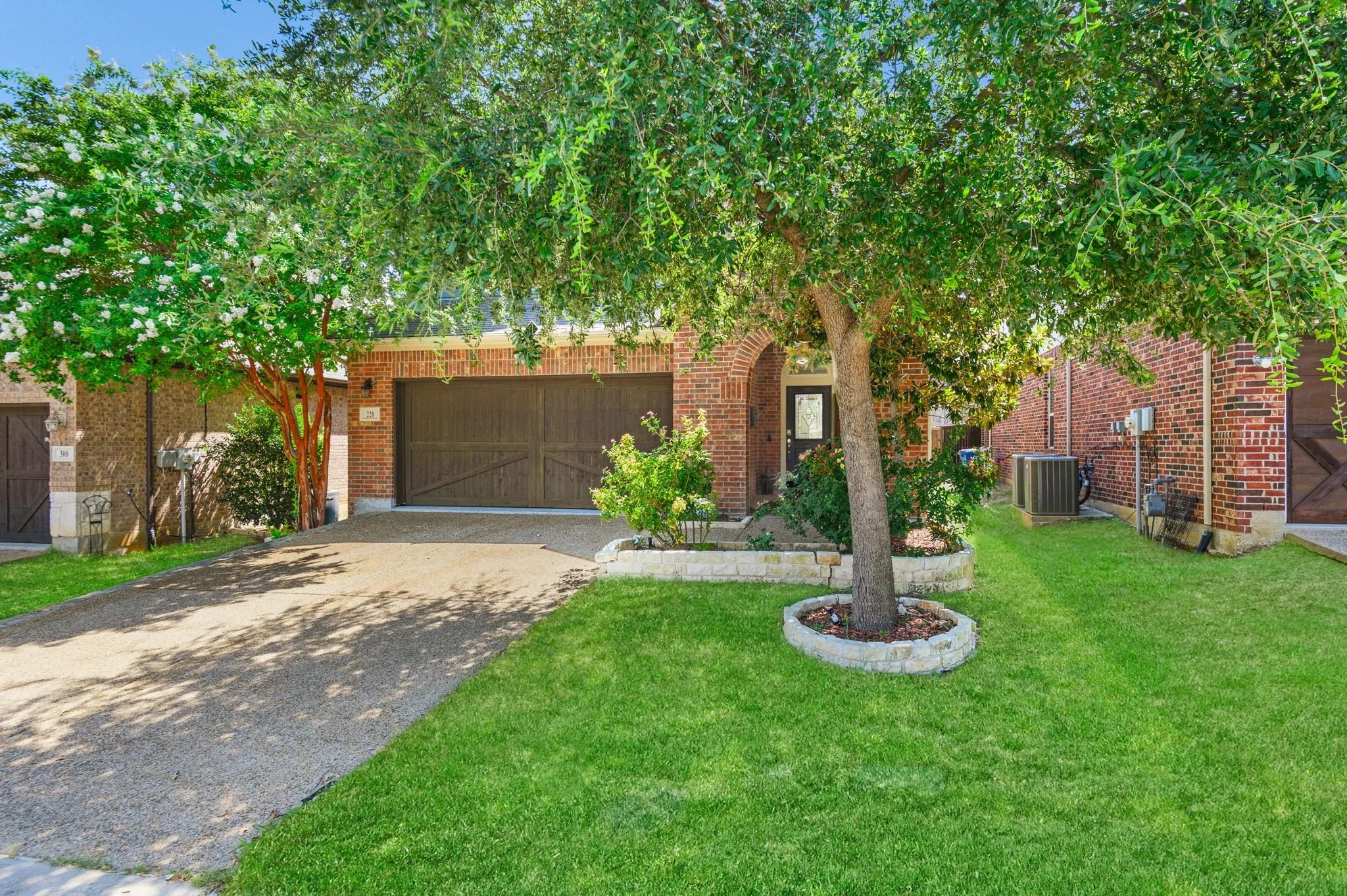 Brick exterior featuring an arched entry, dark wood-finish garage door, and a concrete driveway