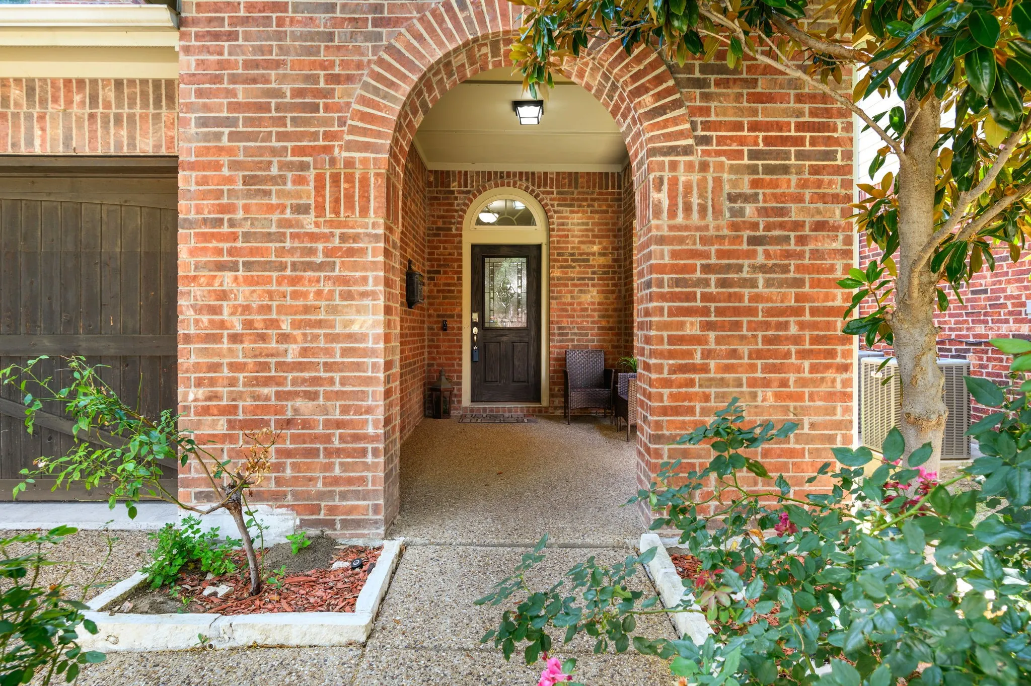 Brick facade featuring an arched entryway with a dark wood door, frosted glass inset, and transom window