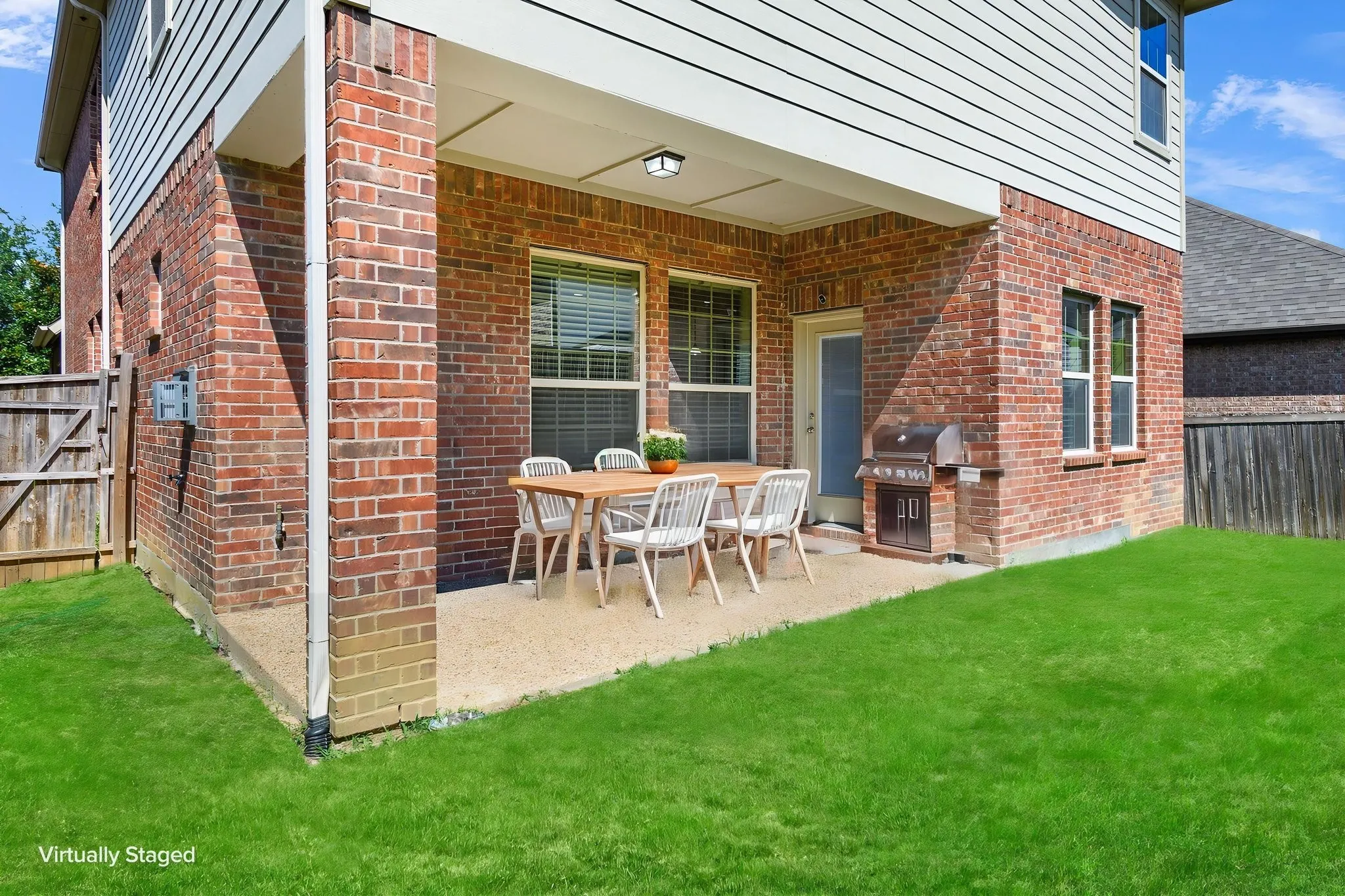 Covered outdoor patio with a textured concrete surface, brick and siding exterior, and direct access to the interior