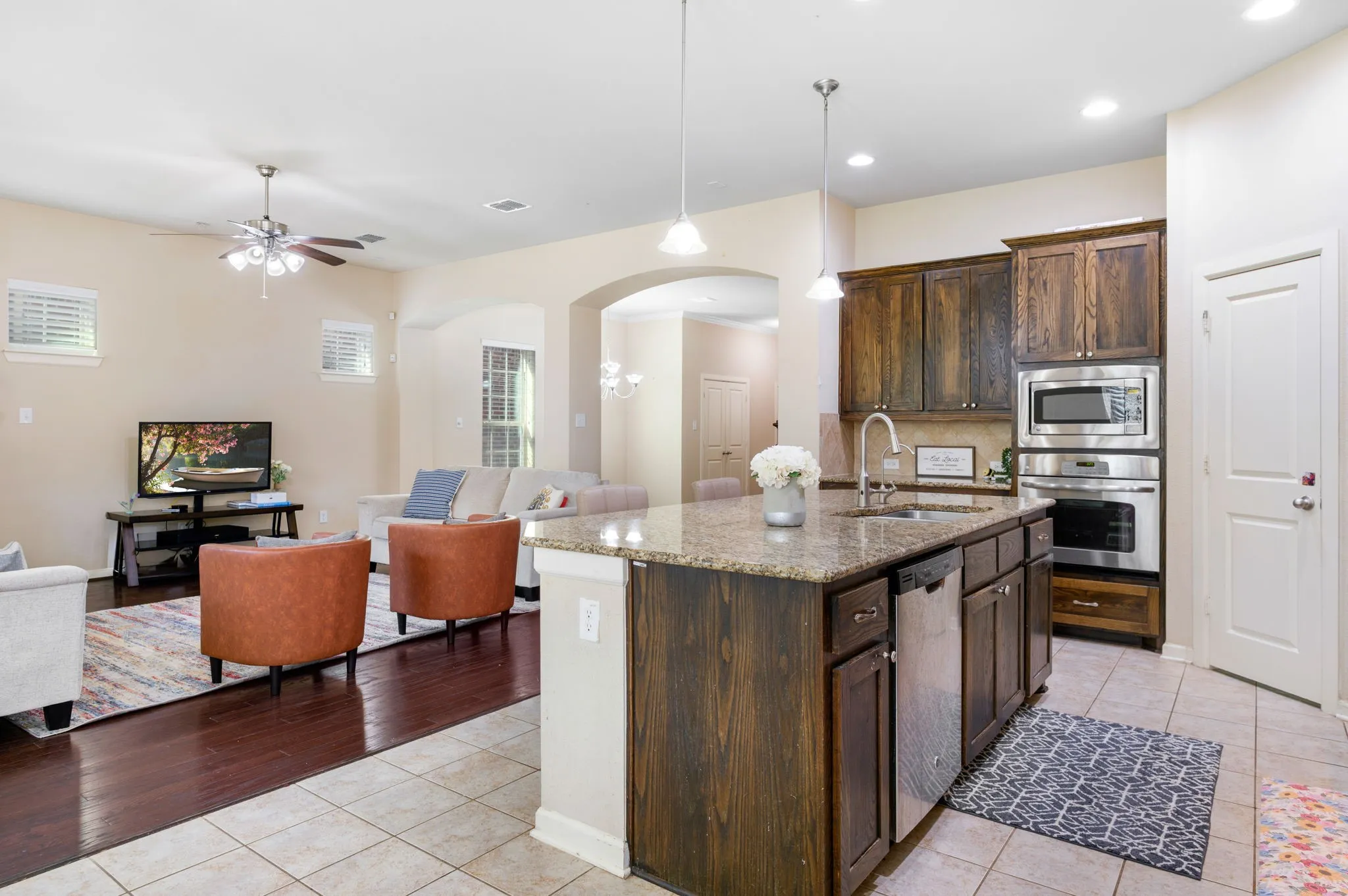 Kitchen island with a light-toned granite countertop, dark wood-finish cabinetry, and stainless steel sink