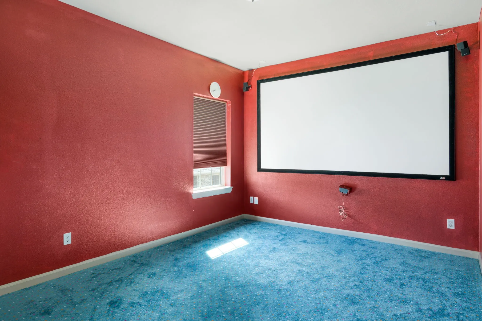 Entertainment room featuring a large projector screen, mounted speakers, and a window with blinds