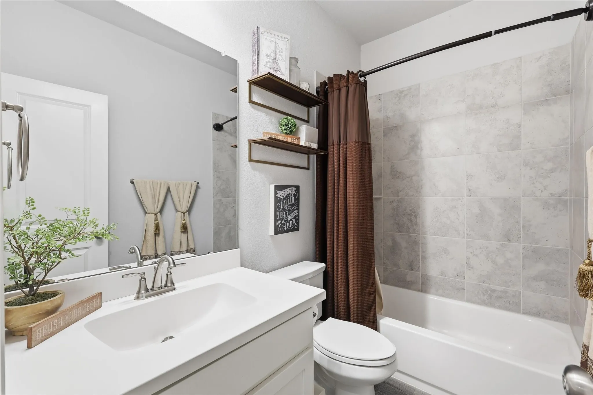 Bathroom featuring a white vanity with an integrated sink, brushed nickel faucet, frameless mirror, and a full bathtub with light-toned tile surround