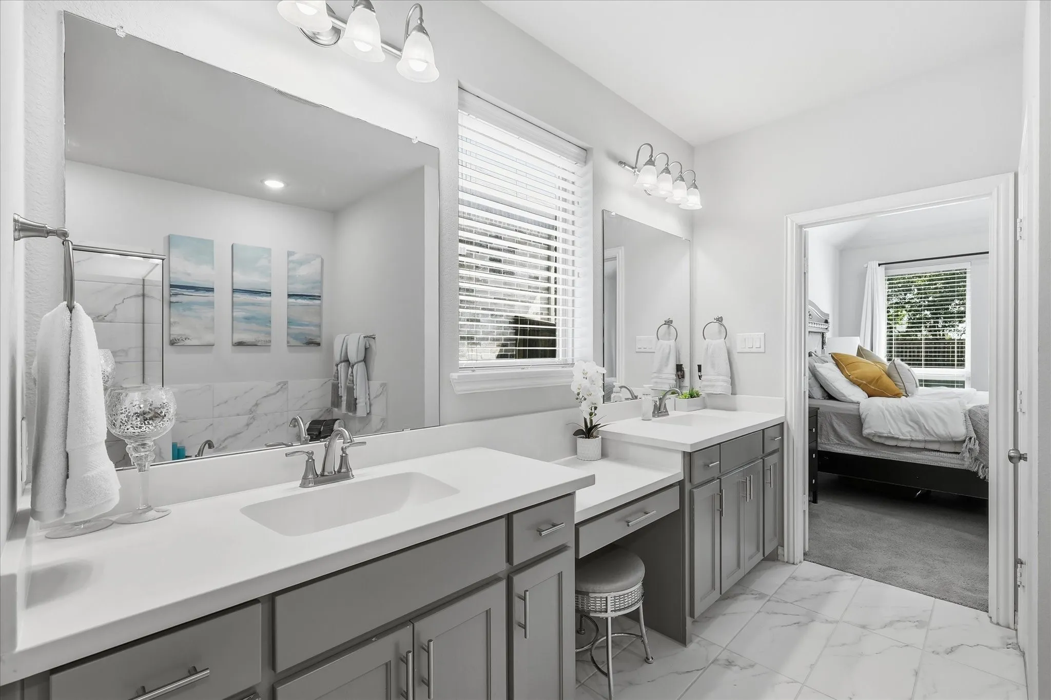 Dual vanity with undermount sinks, gray cabinetry, and white countertops and separate tub and walk in shower with large closet