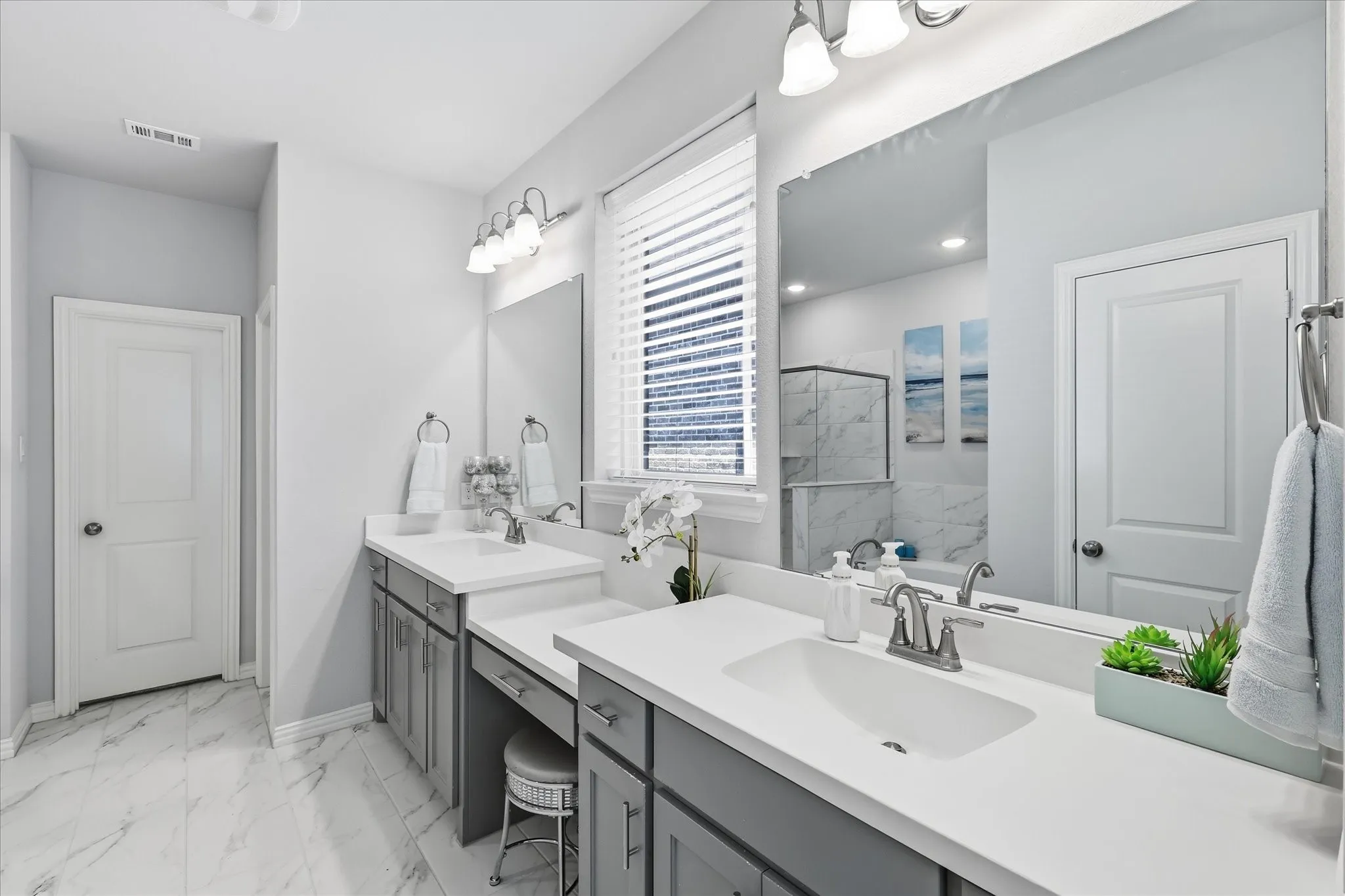 Dual vanity with undermount sinks, gray cabinetry, and white countertops and separate tub and walk in shower with large closet