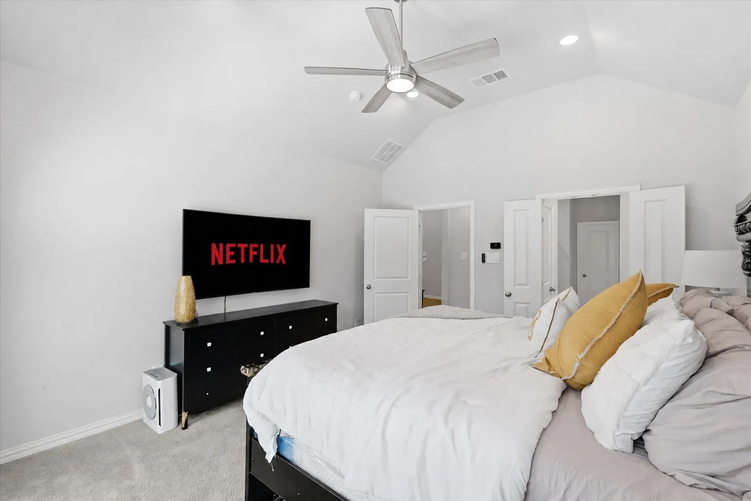 Large primary bedroom featuring a vaulted ceiling with a ceiling fan, recessed lighting with sitting room and large amount of natural light