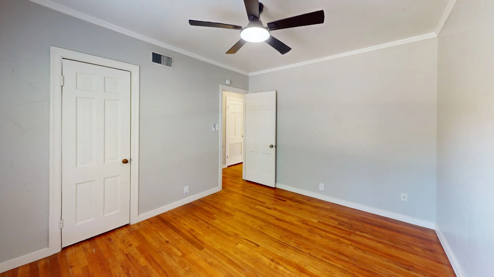 Spacious room featuring wood-finish flooring and light gray walls