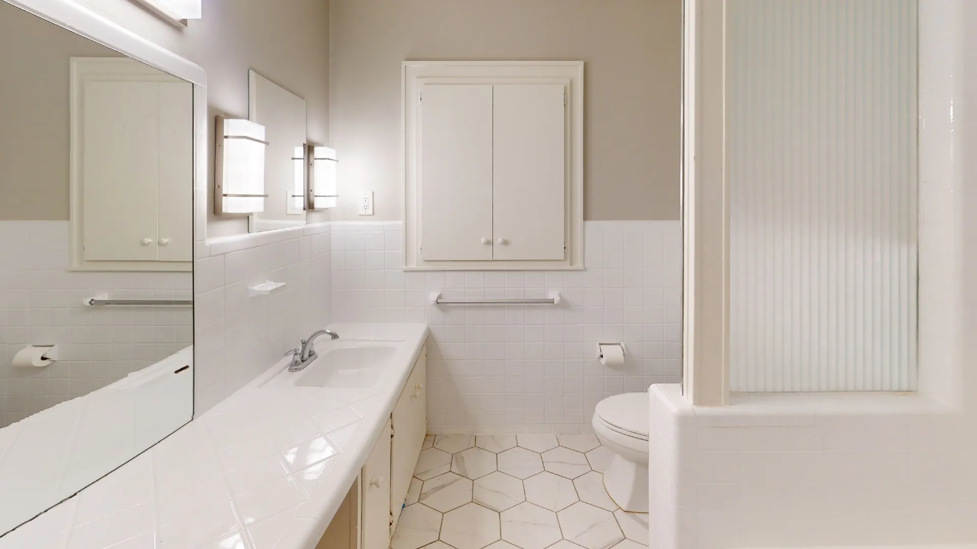 Bathroom featuring a white ceramic tile vanity with integrated sink, hexagon tile flooring, and white subway tile wainscoting