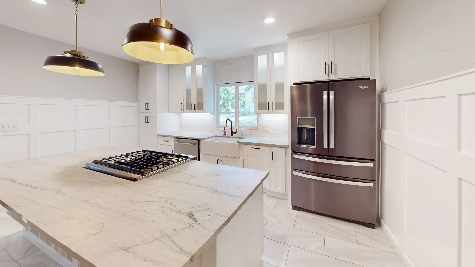 Modern kitchen featuring a large island with an integrated gas cooktop, white shaker cabinetry, stainless steel appliances, a farmhouse sink, and contemporary pendant lighting