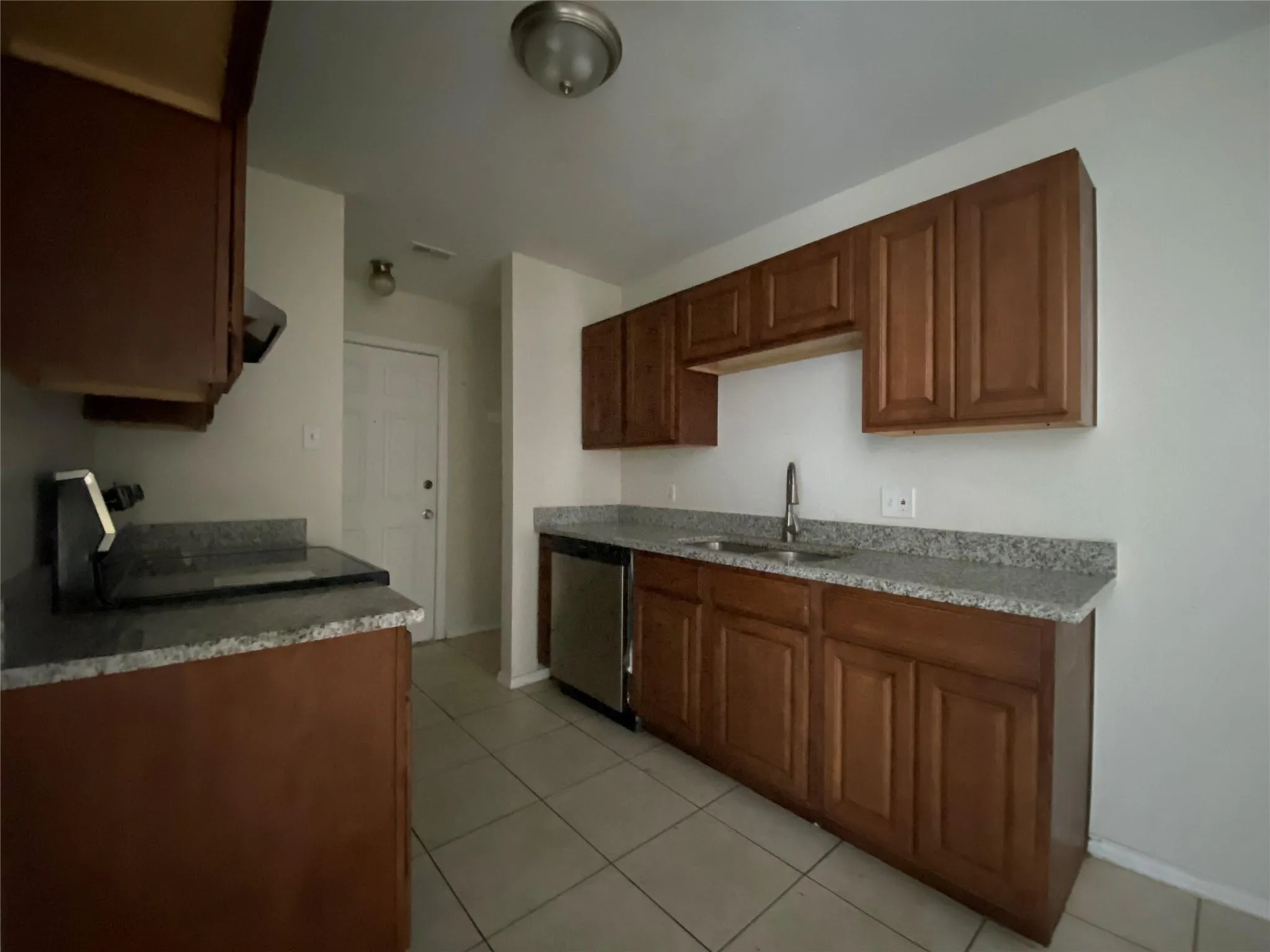 Kitchen featuring sink, stainless steel dishwasher, ventilation hood, light tile patterned floors, and range