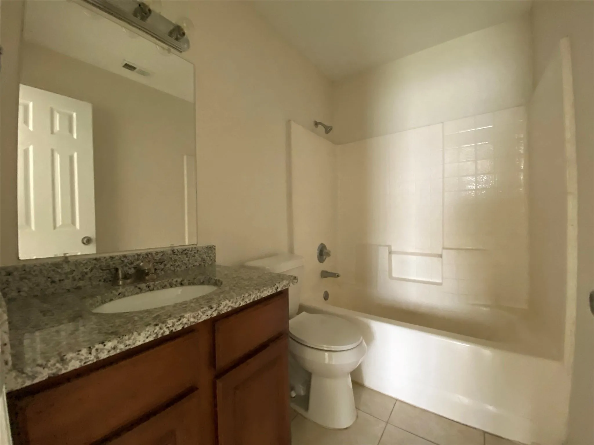 Full bathroom featuring tile patterned flooring, vanity, toilet, and washtub / shower combination
