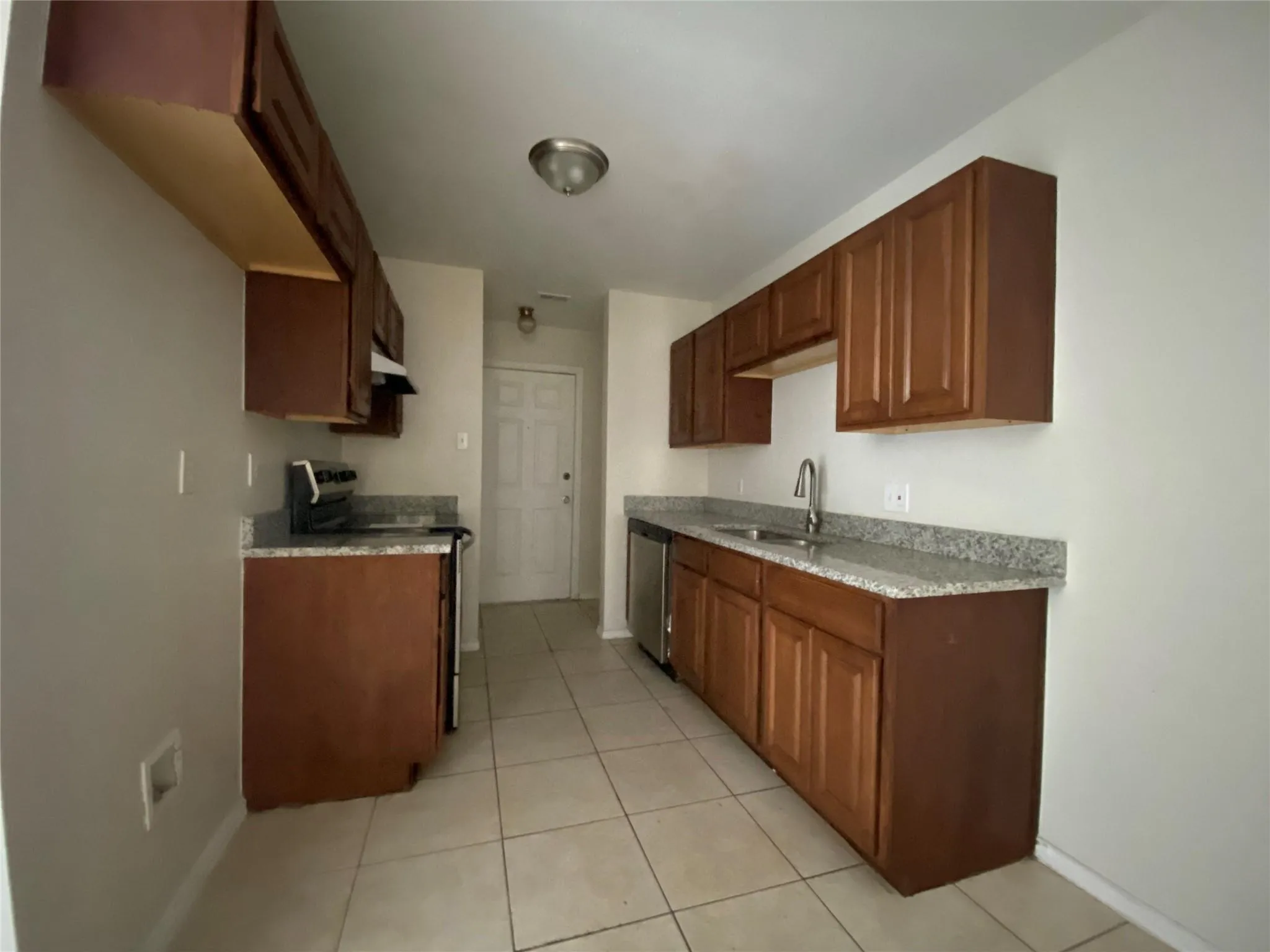 Kitchen with stainless steel dishwasher, range with electric stovetop, light tile patterned flooring, and sink