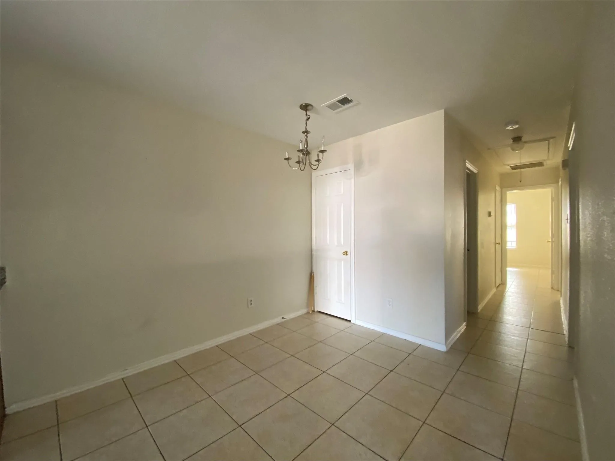 Unfurnished room with a notable chandelier and light tile patterned flooring