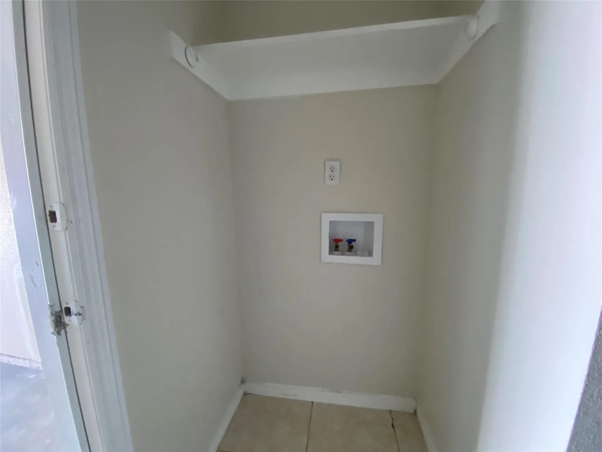 Laundry room with hookup for a washing machine and light tile patterned floors