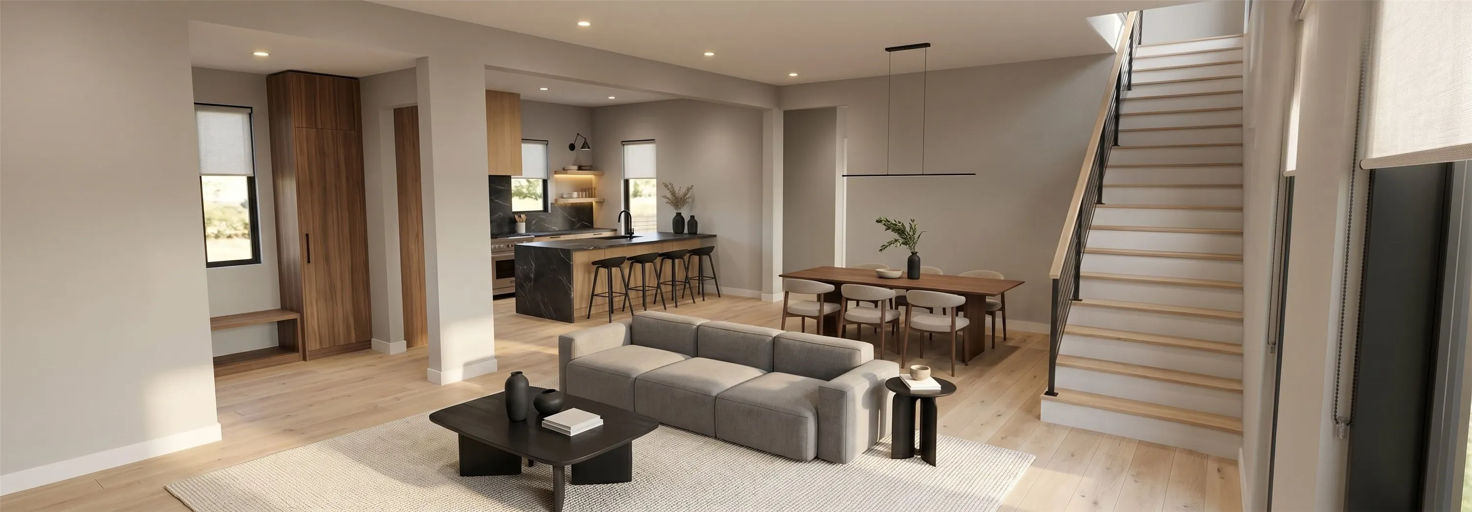 Spacious open-concept living area featuring light wood-finish flooring, a modern kitchen with a large dark stone island, and a separate dining area with a linear pendant light